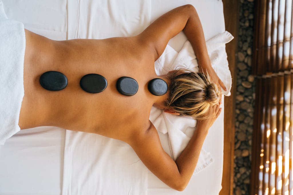 A serene hot stone massage therapy session with smooth black stones placed on the back for relaxation.
