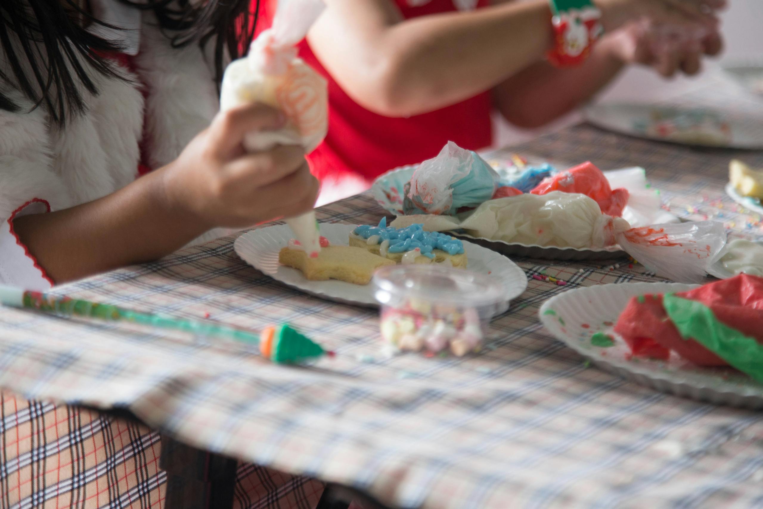 Children decorating cookies with colorful icing during a festive Christmas activity.
