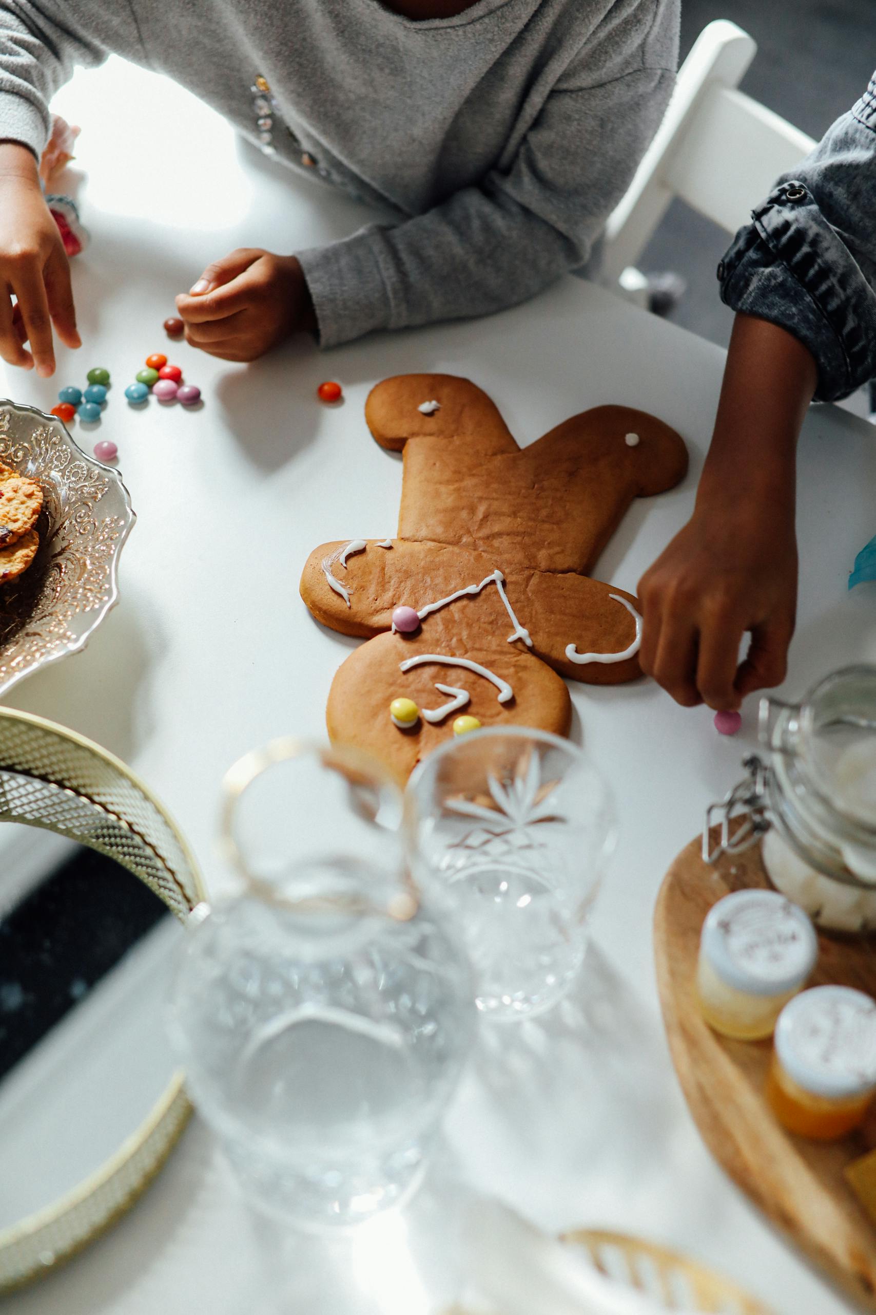 Kids decorating big homemade gingerbread man cookies.