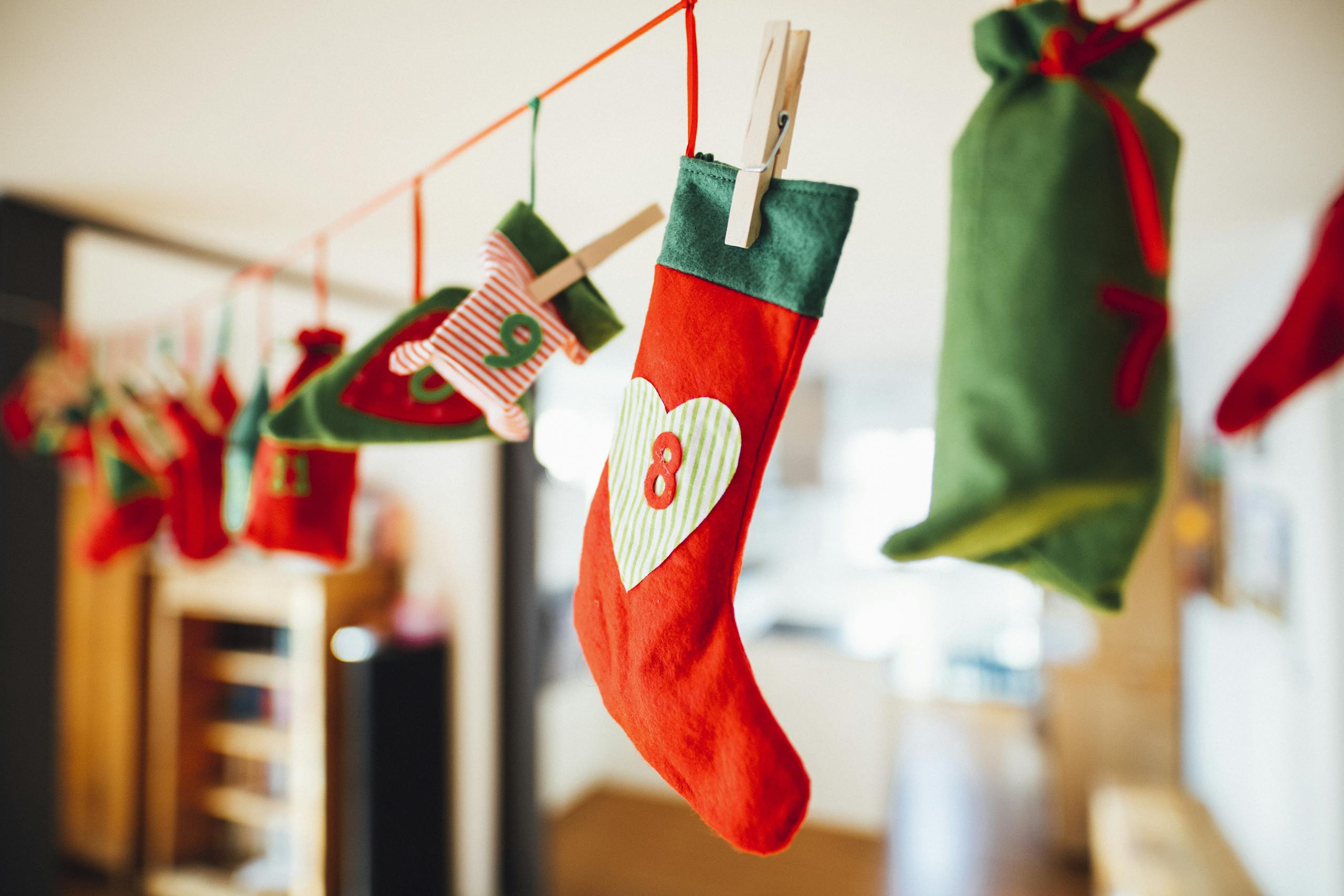 Vibrant Christmas stockings hang on a clothesline indoors, creating festive holiday decor.