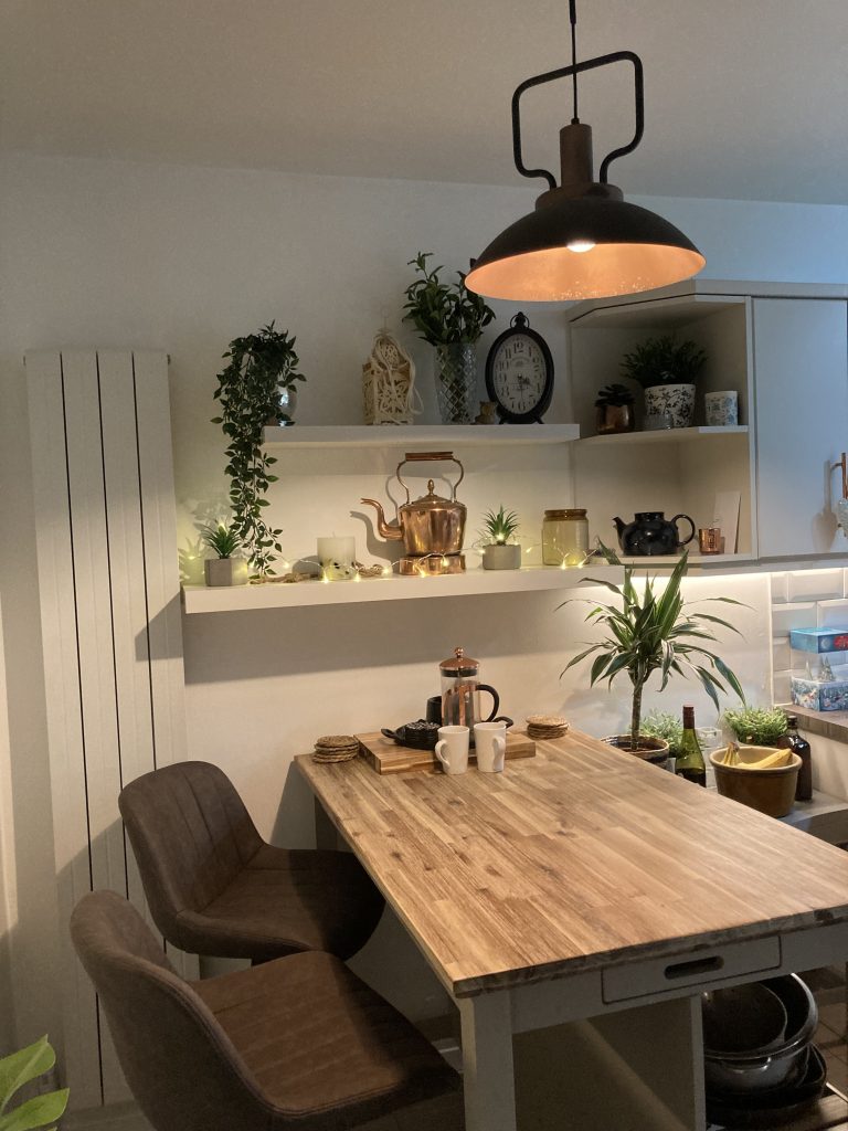 a cozy kitchen free standing work station, with shelves above and fairy lights.