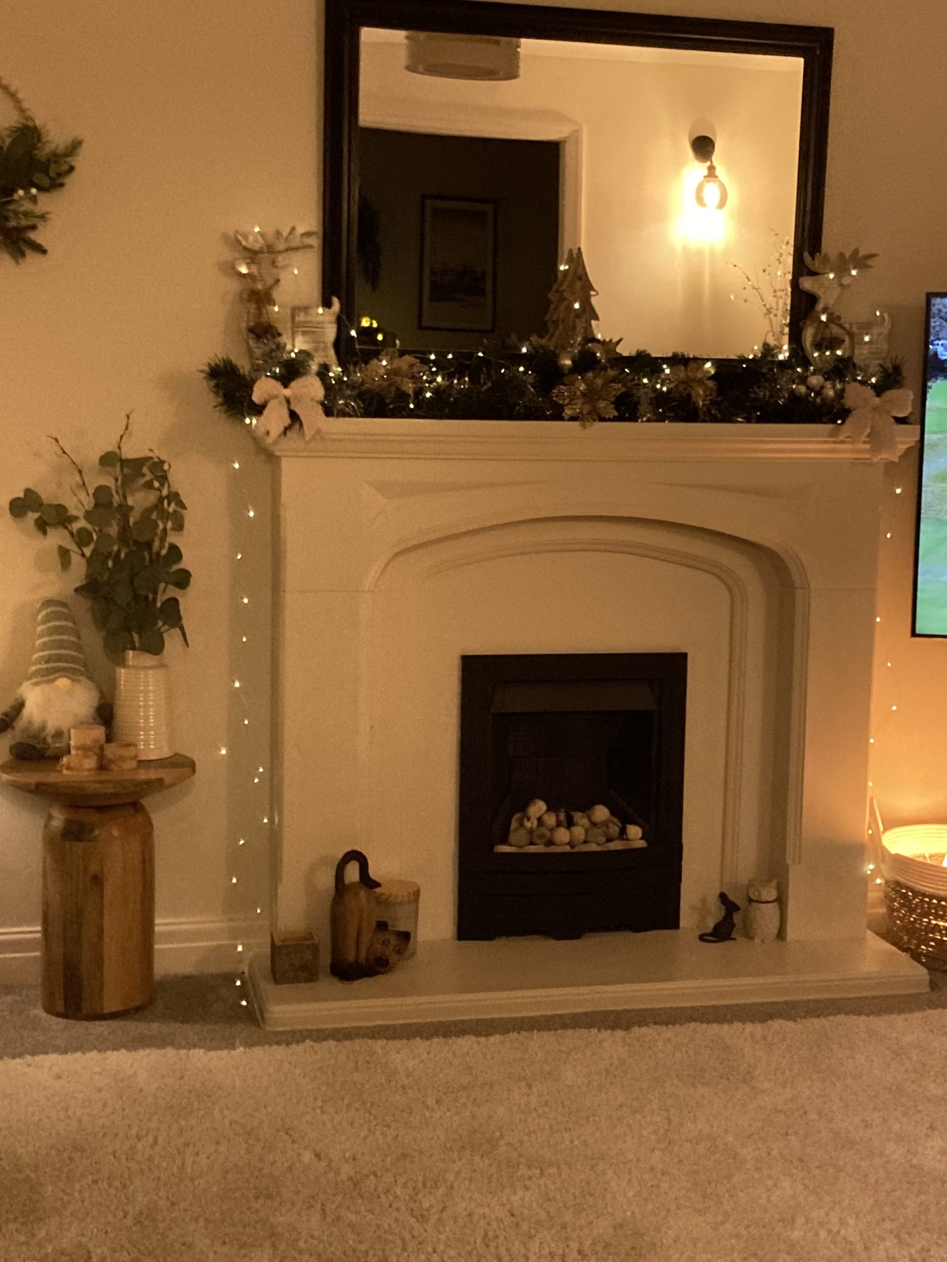 warm white fairy lights around a mirror over a mantle fire place with log burner in a shabby chic living room with soft sofa and chucky throws on the sofa