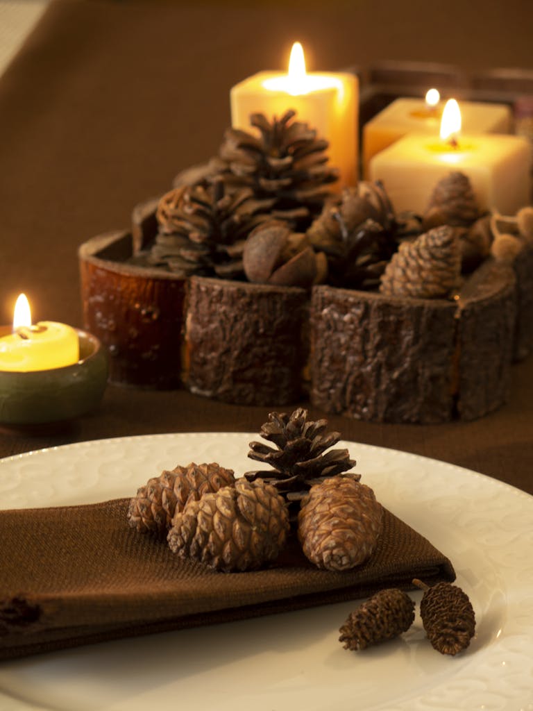 Autumn candles burning on rustic wooden table with fallen leaves