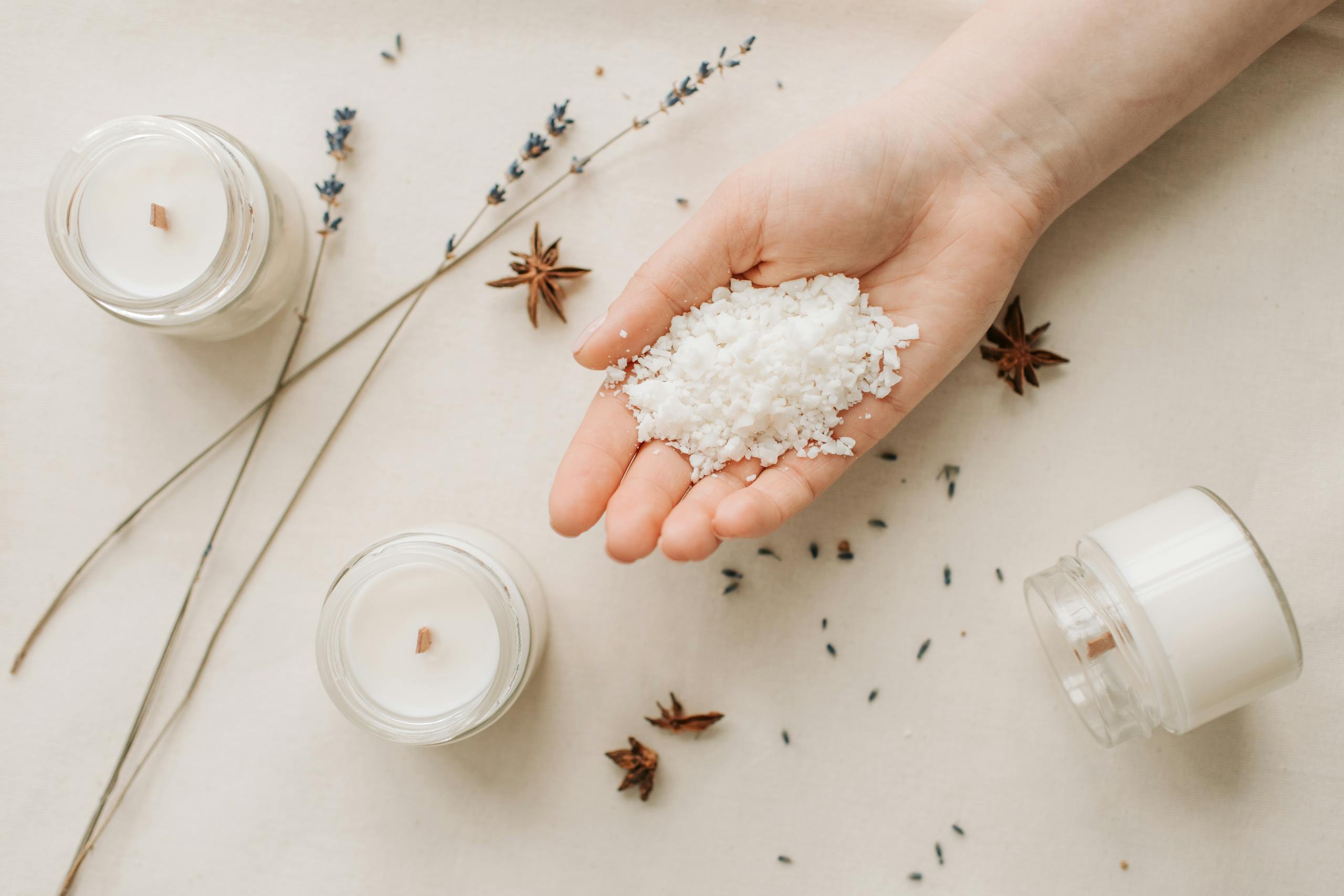Flat lay of natural candle making with granulated wax, star anise, and lavender on a beige background.