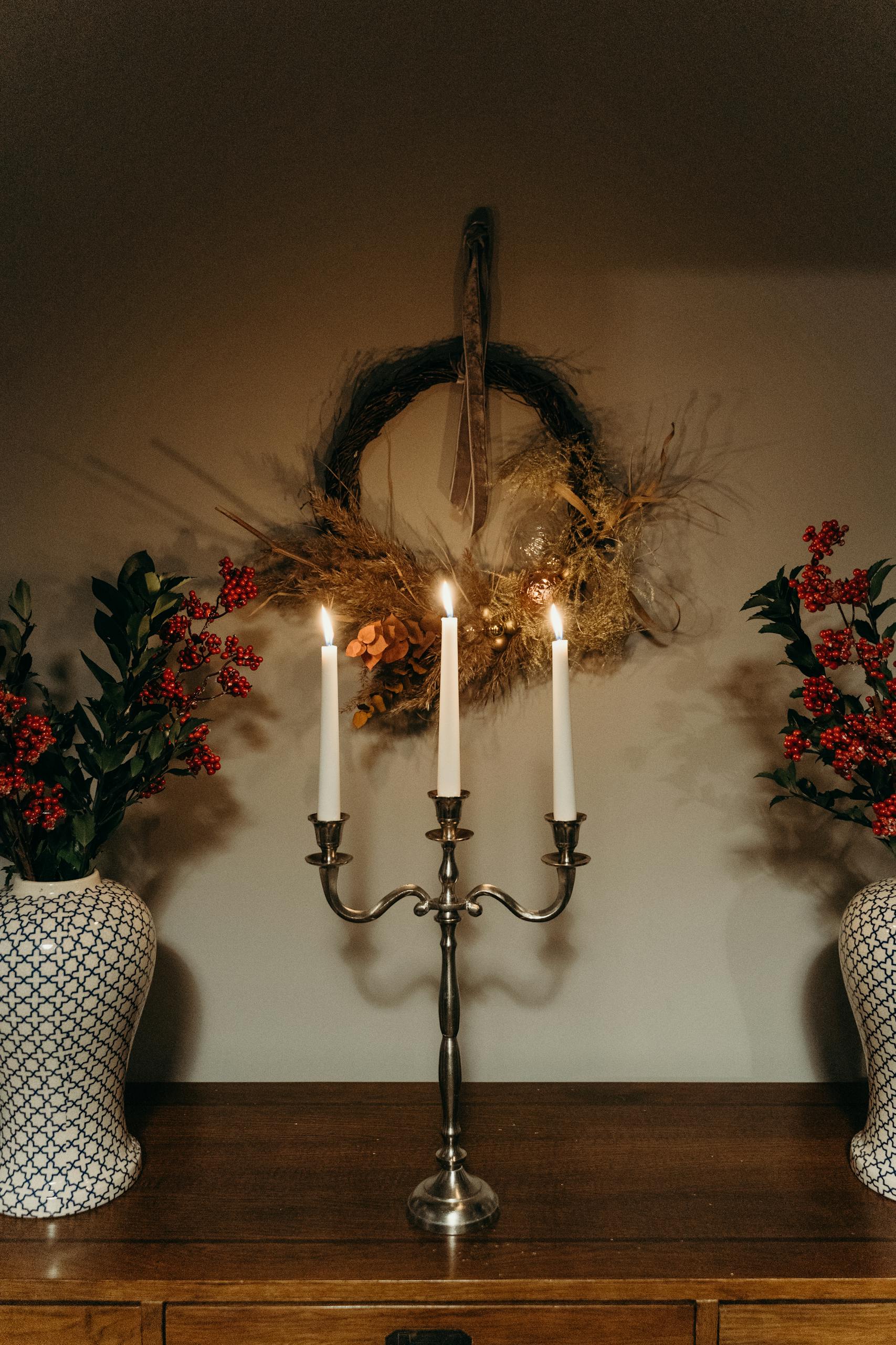 A beautifully arranged candlelit centerpiece with floral vases and a rustic wreath.