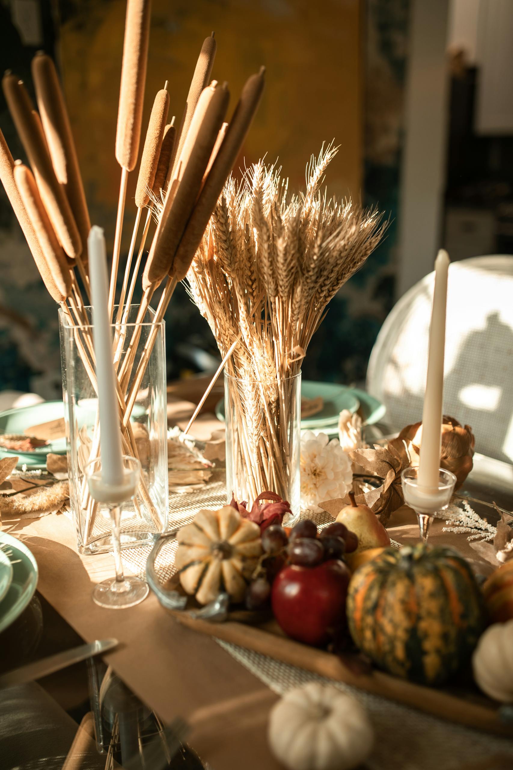 A beautifully arranged fall table setting featuring candles, gourds, and wheat for a festive atmosphere.