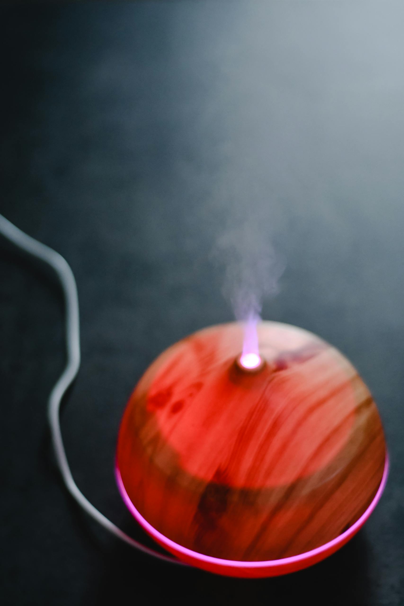A wooden aromatherapy diffuser emitting mist with a pink glowing light, creating a soothing ambiance.