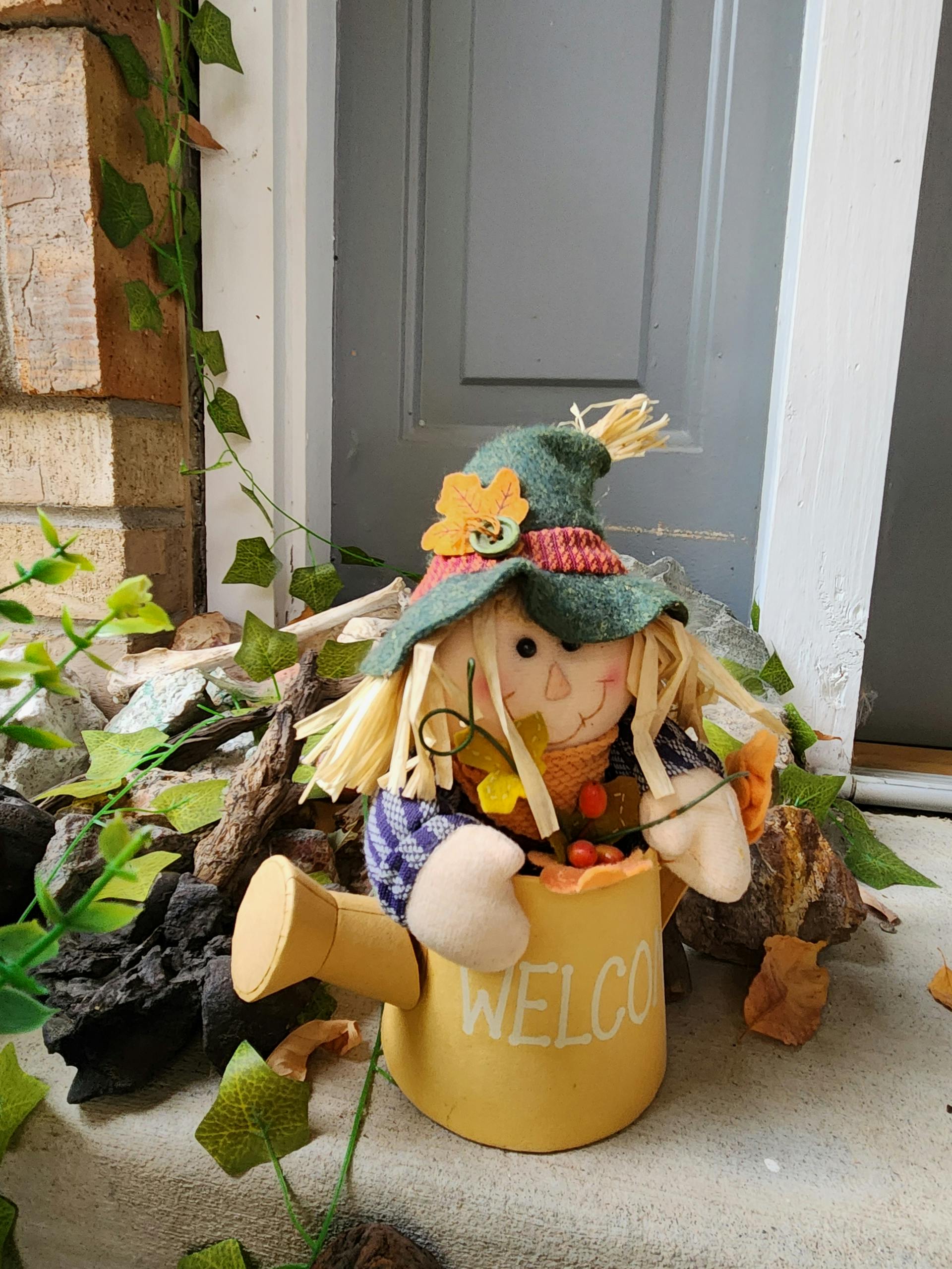 Charming scarecrow decoration in autumn theme greets visitors with a warm welcome on a cozy porch.
