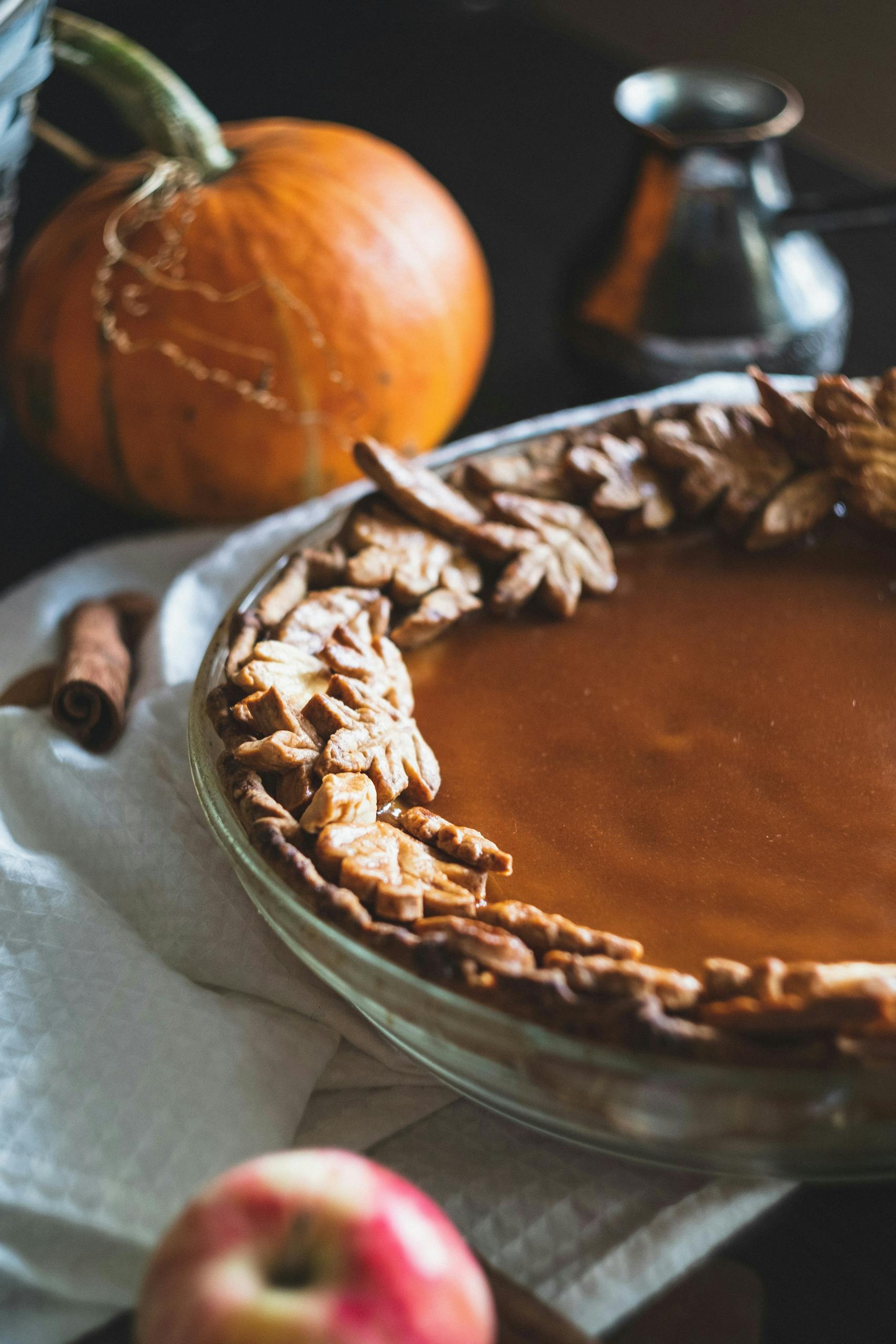 Close-up of a pumpkin pie surrounded by autumn decorations, perfect for Halloween themed settings.