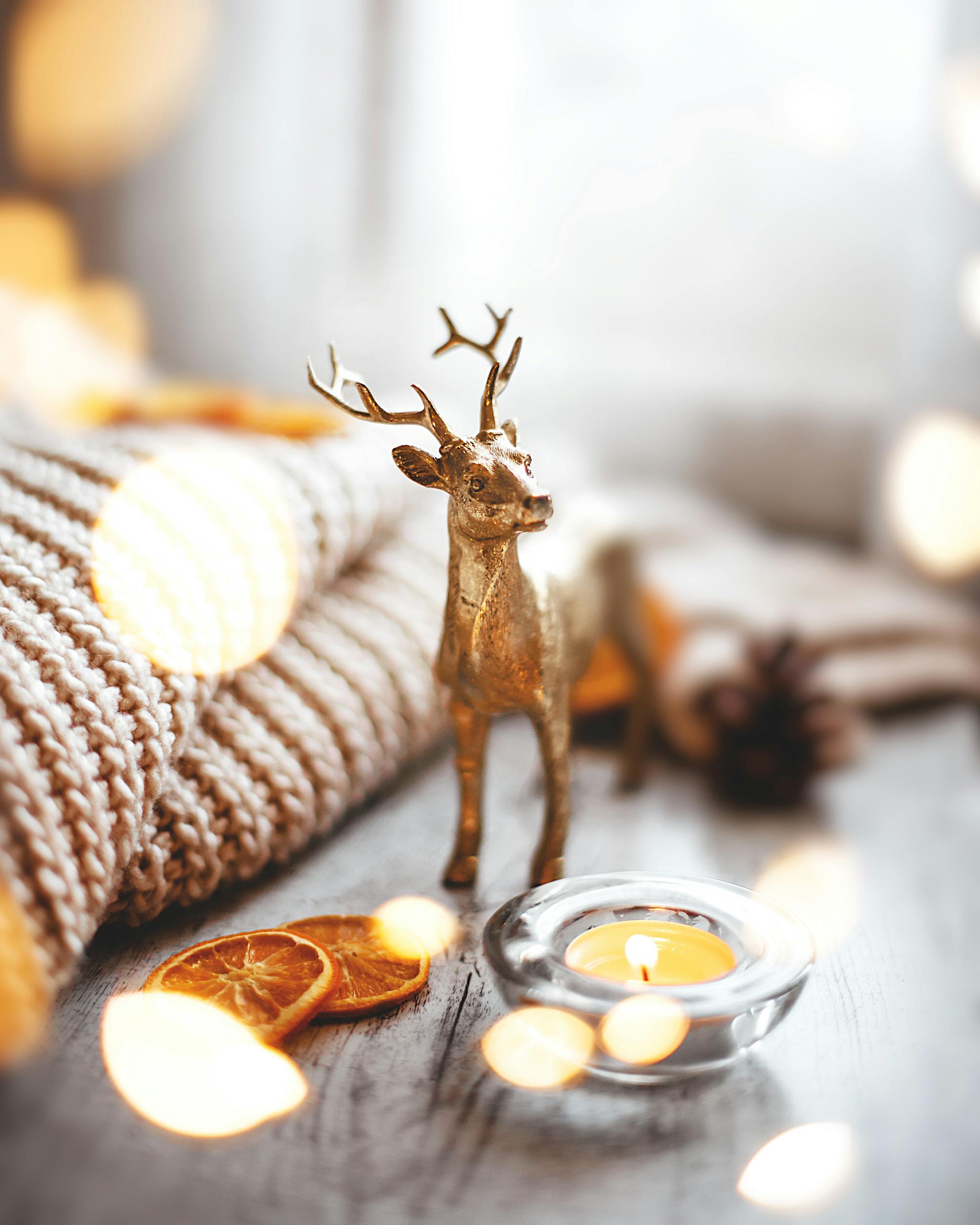 Autumn to Christmas Transition Golden deer figurine with candle and dried orange slices on a cozy winter setup.