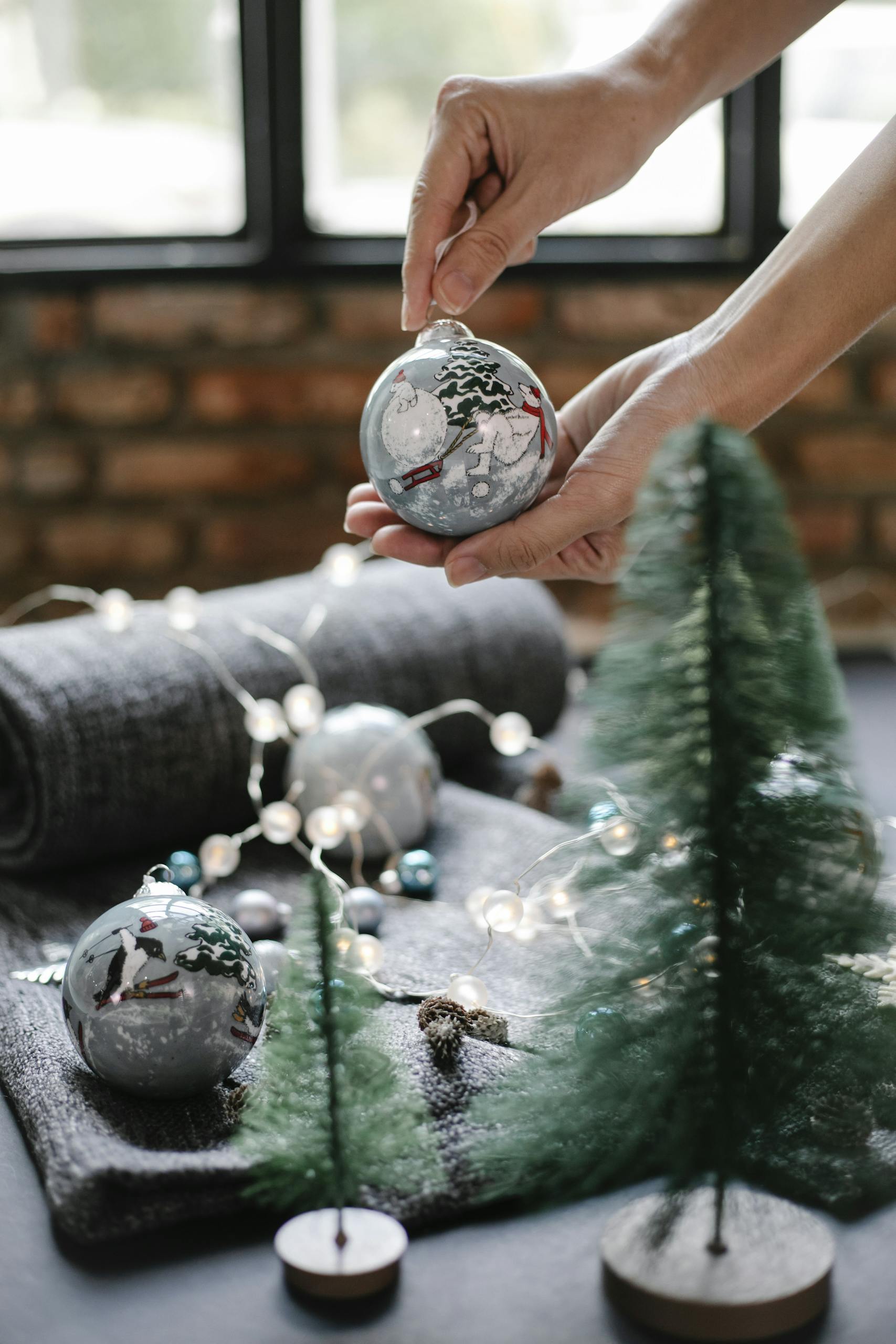 Hands decorating holiday ornaments in a festive, cozy setting.