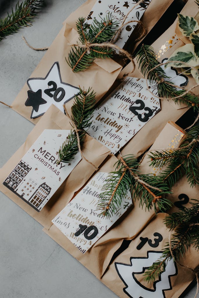 Top view of a Christmas advent calendar made with decorated paper bags and evergreen sprigs.