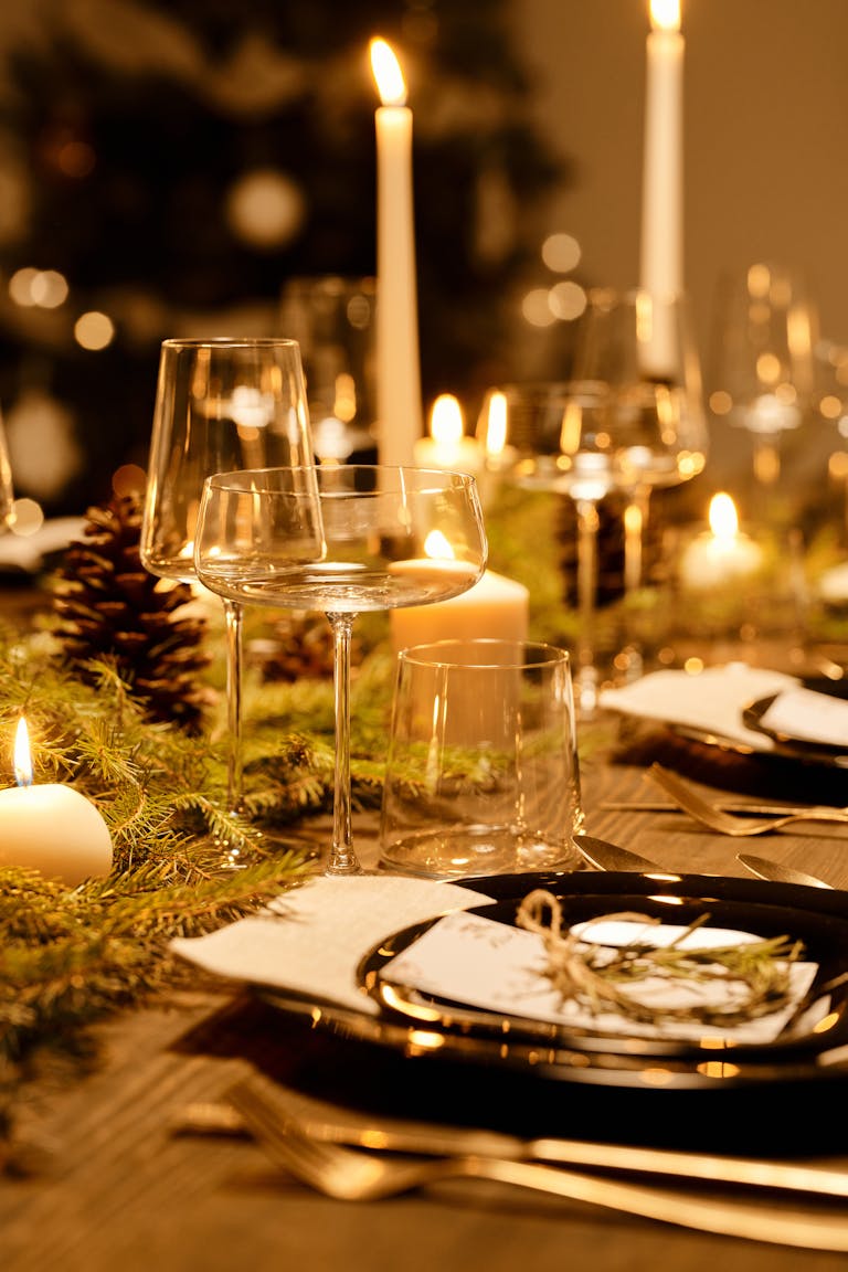 Warm and elegant Christmas dinner table decorated with candles and greenery, perfect for the holiday season.