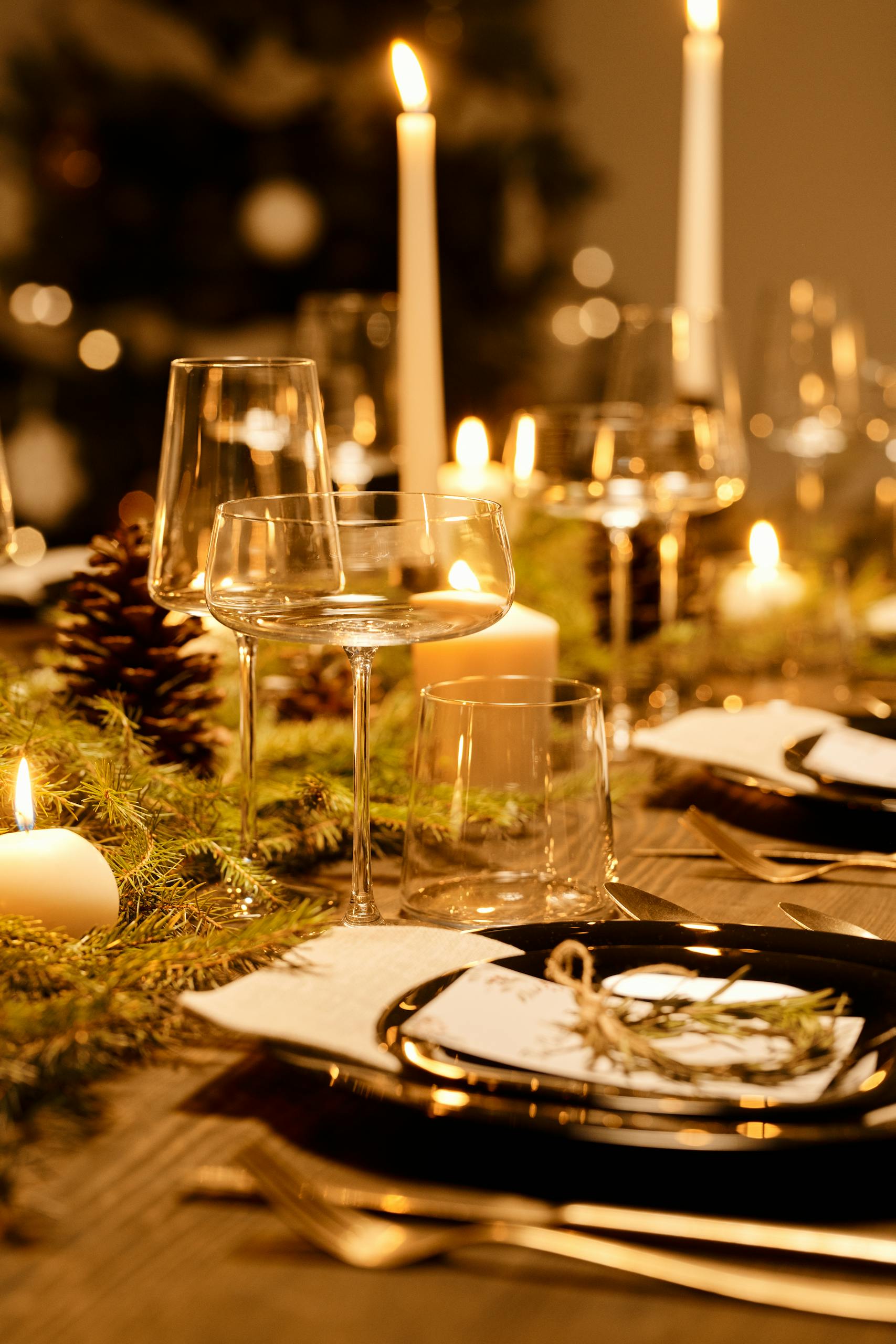 Warm and elegant Christmas dinner table decorated with candles and greenery, perfect for the holiday season.