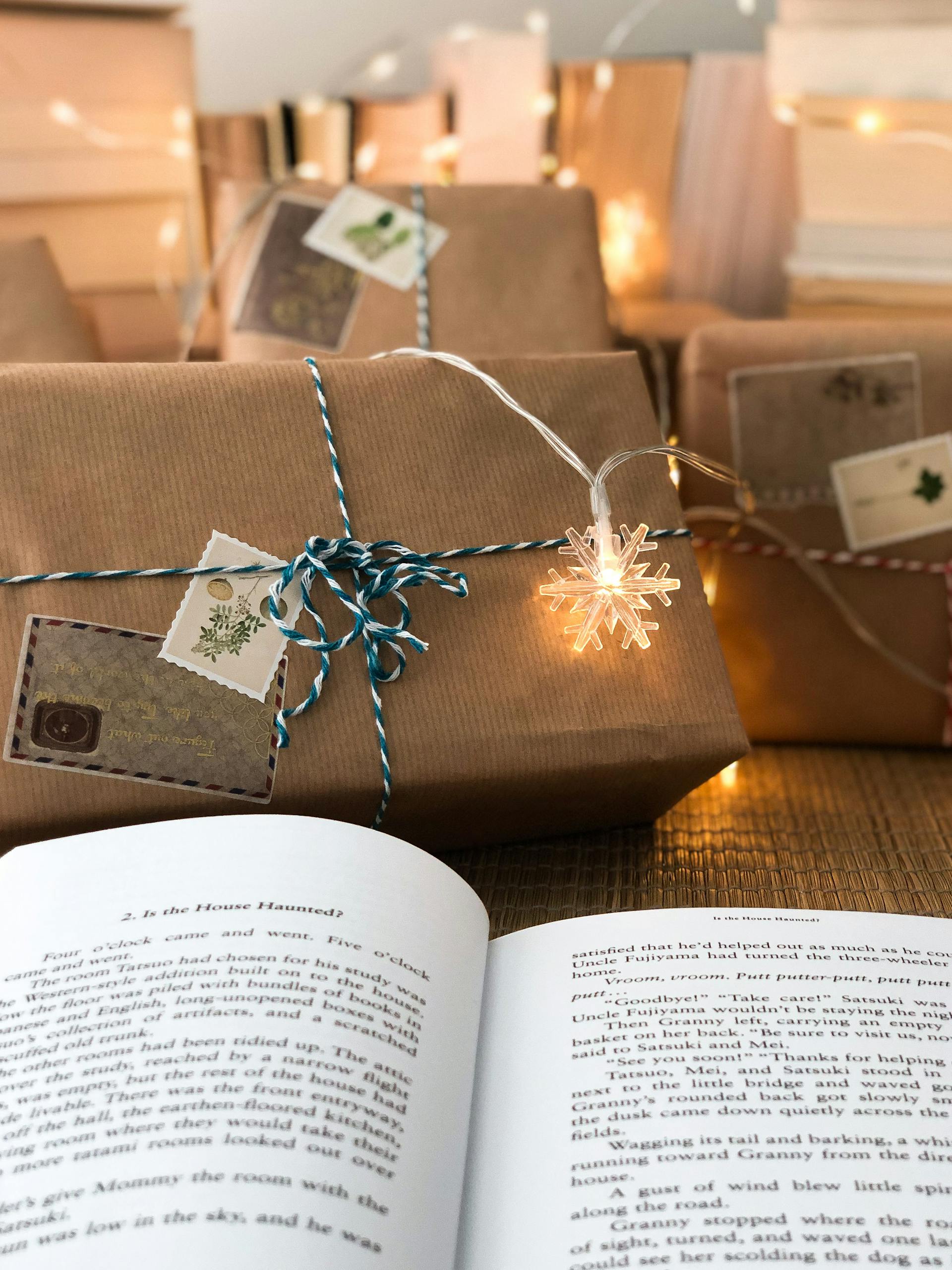 Warm holiday scene with wrapped gifts, a book, and twinkling lights for Christmas inspiration.