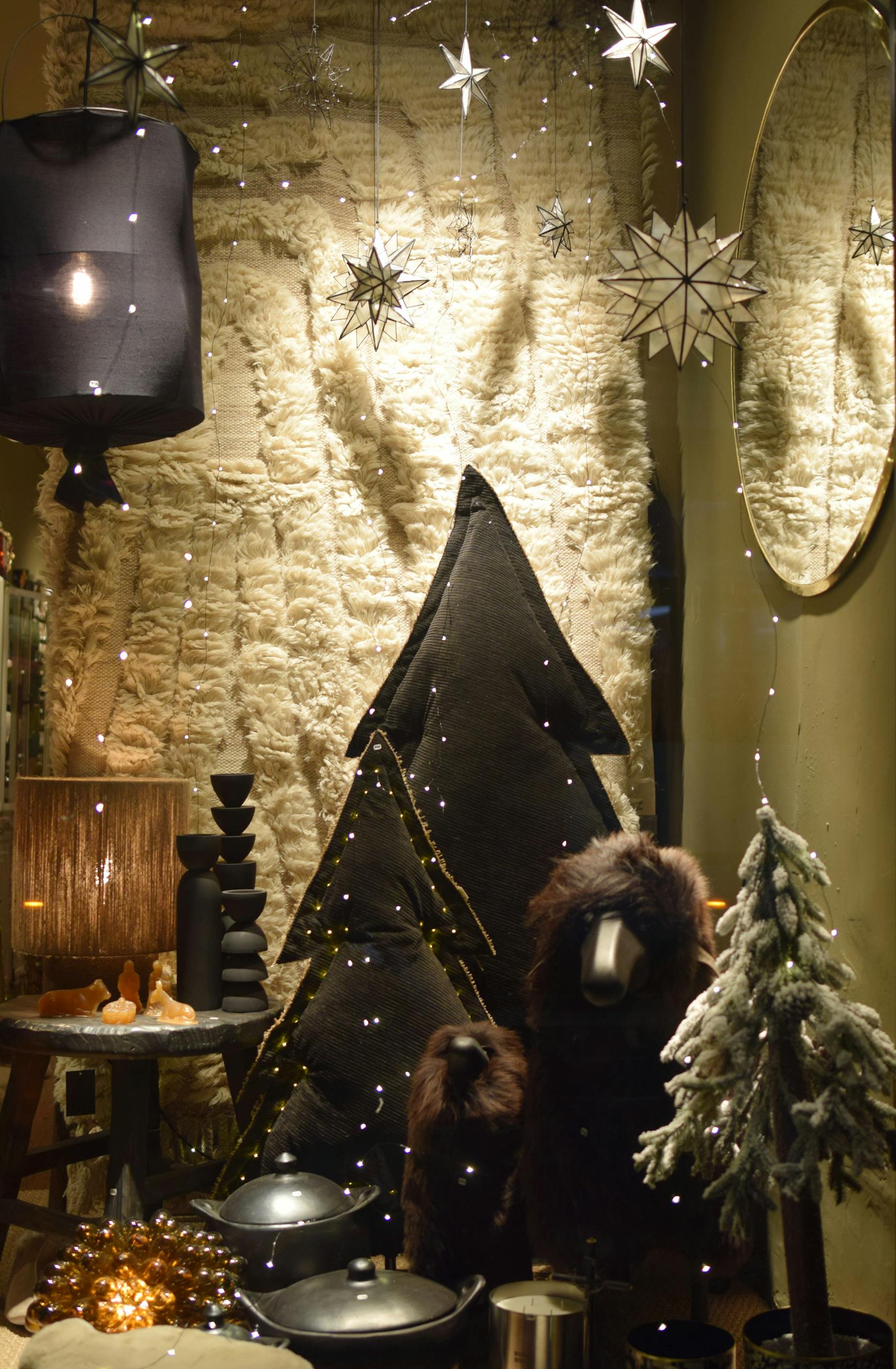 Warm holiday-themed window display with decorative trees and lights.