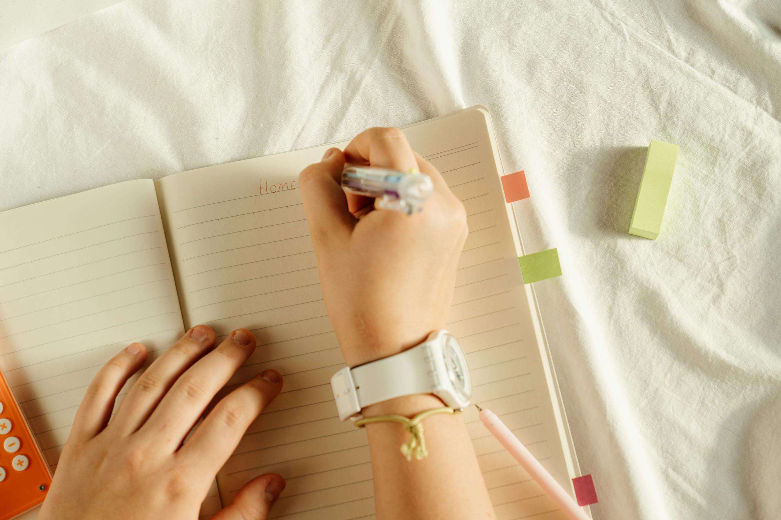A close-up view of hands writing notes in a notebook with a pen, ideal for party check list
