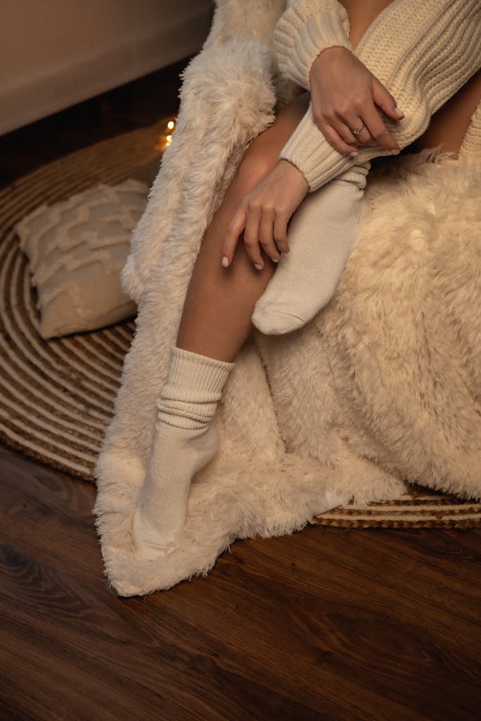 A cozy indoor setting featuring a woman wrapped in a fluffy blanket, exuding warmth and comfort.