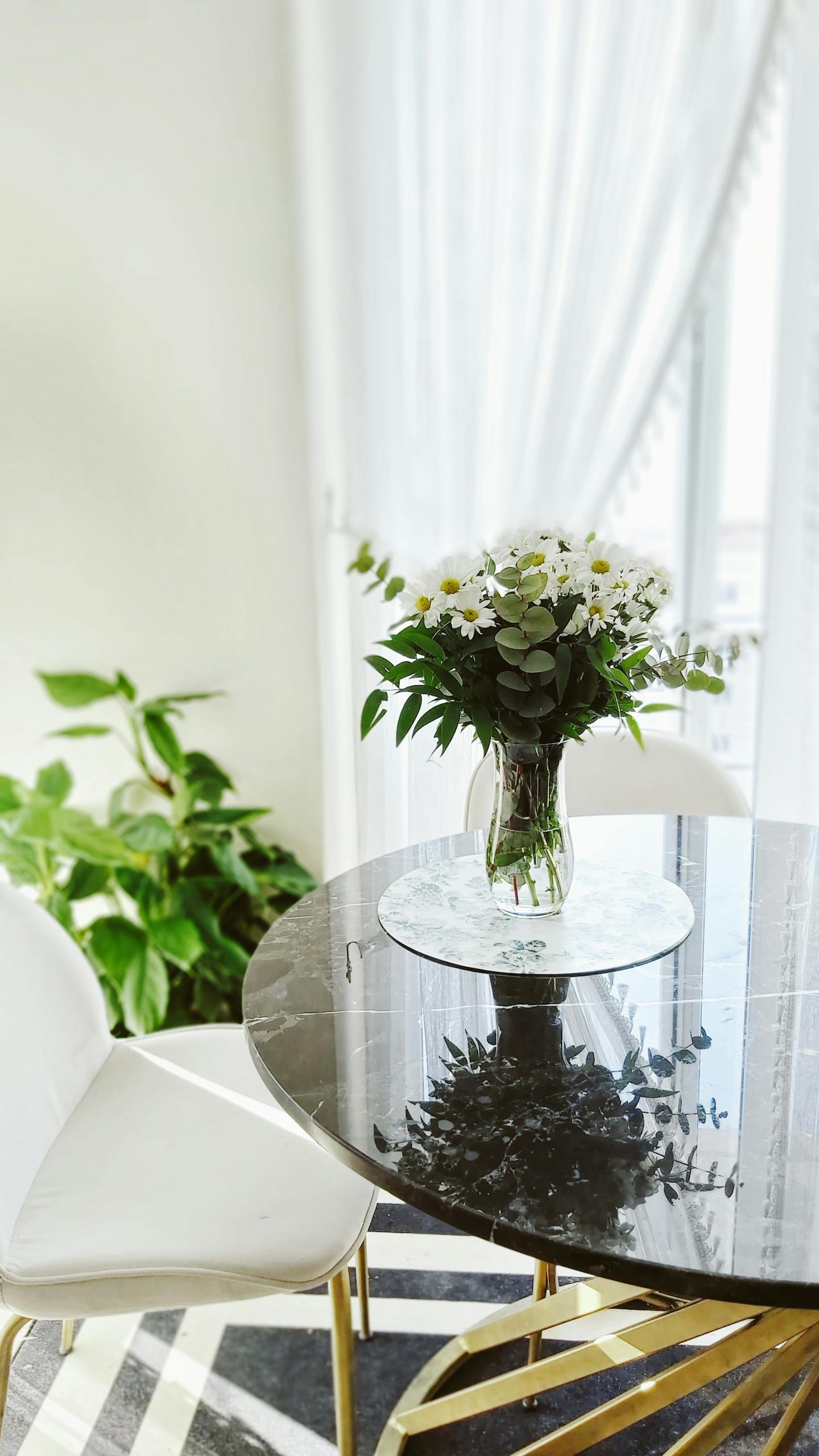 A stylish interior with flowers in a vase on a marble-top table, offering a modern decorative touch.