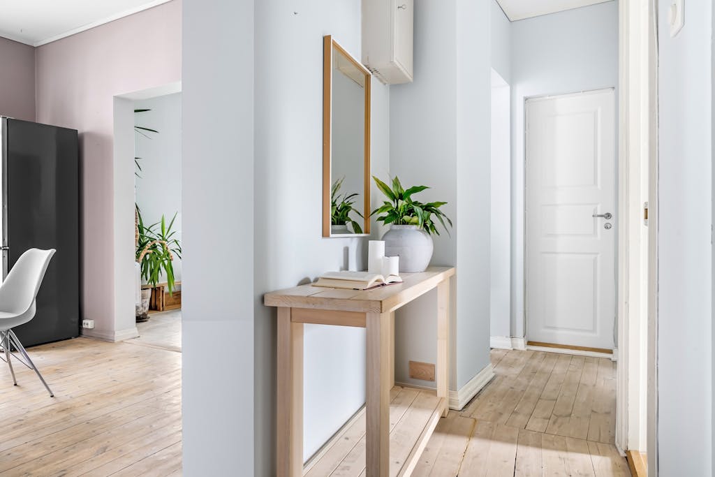 Bright hallway interior featuring minimalist decor, a mirror, and lush plants for a serene ambiance.