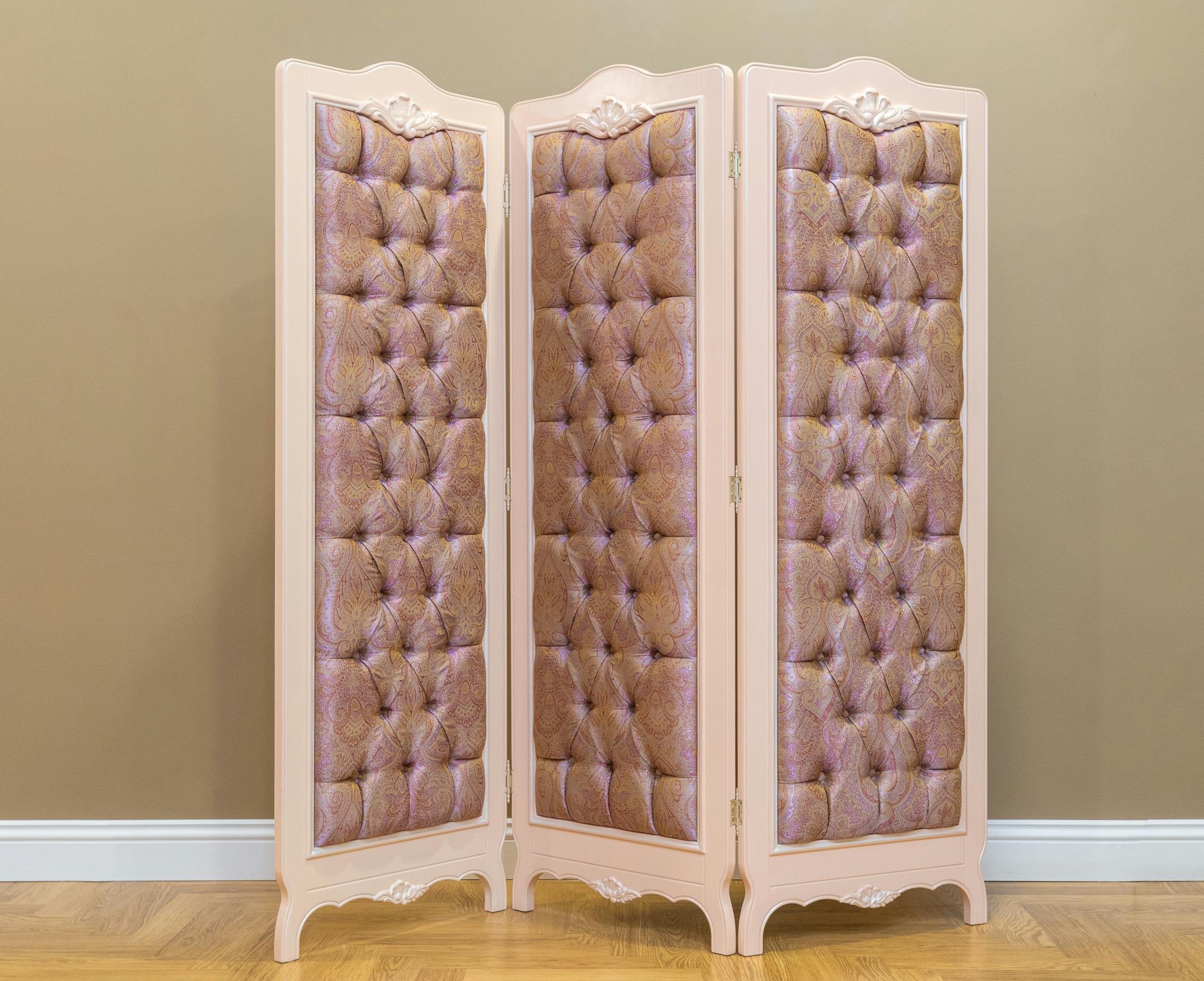 Elegant tufted wardrobe screen in classic dressing room with wooden floor, adding style and privacy.