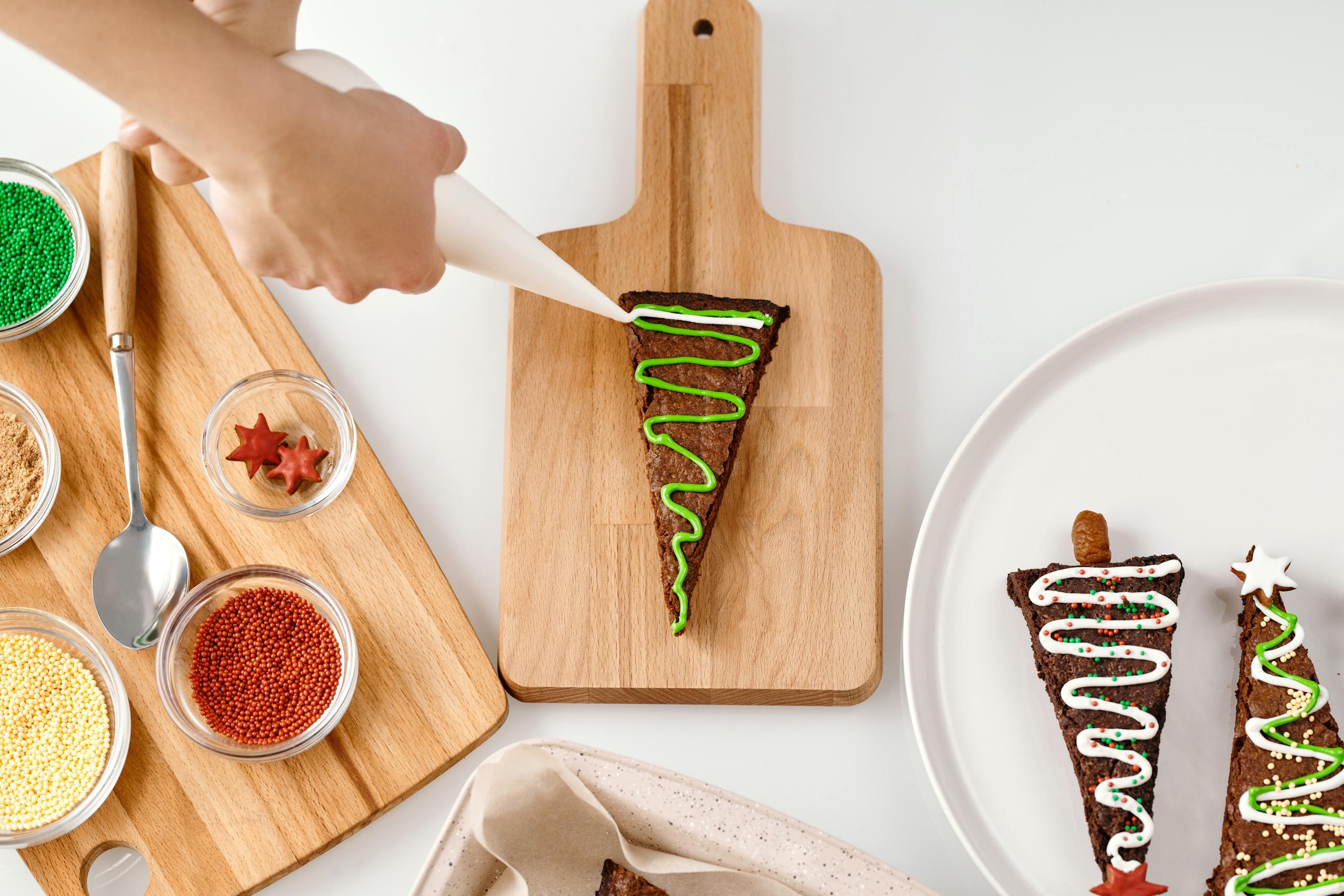 Festive Christmas cookies being decorated with colorful icing on a wooden board.
