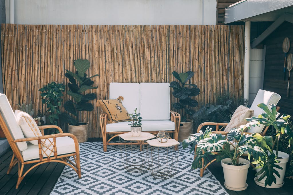 Serene outdoor patio featuring rattan furniture, potted plants, and bamboo decor for a backyard staycation garden