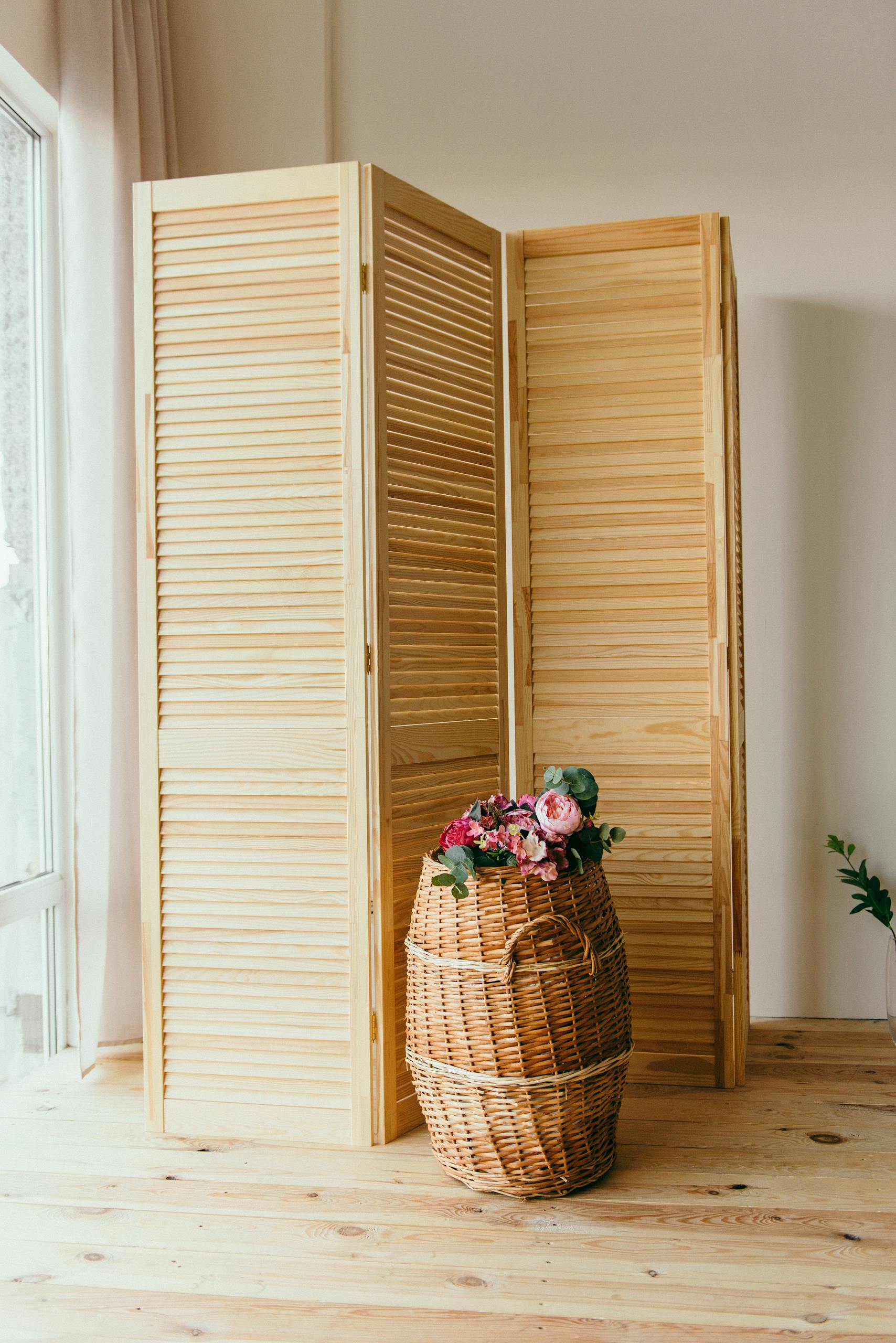 Stylish interior featuring a wooden room divider and decorative basket with flowers.
