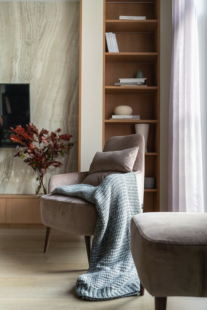 Stylish modern living room featuring a cozy chair, blanket, and elegant decor elements.