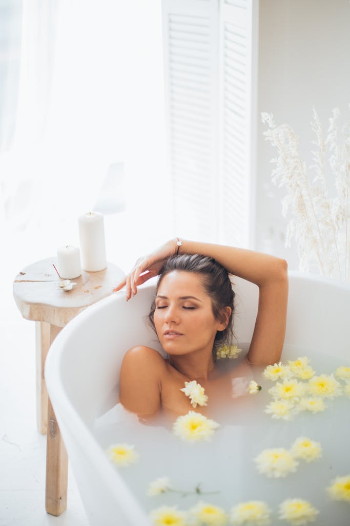 Woman enjoying a soothing bath with yellow flowers and candles, embracing relaxation.