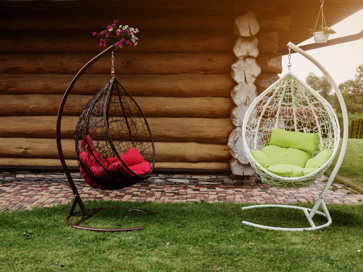 One Black and one white free standing egg chair swings on a green garden lawn