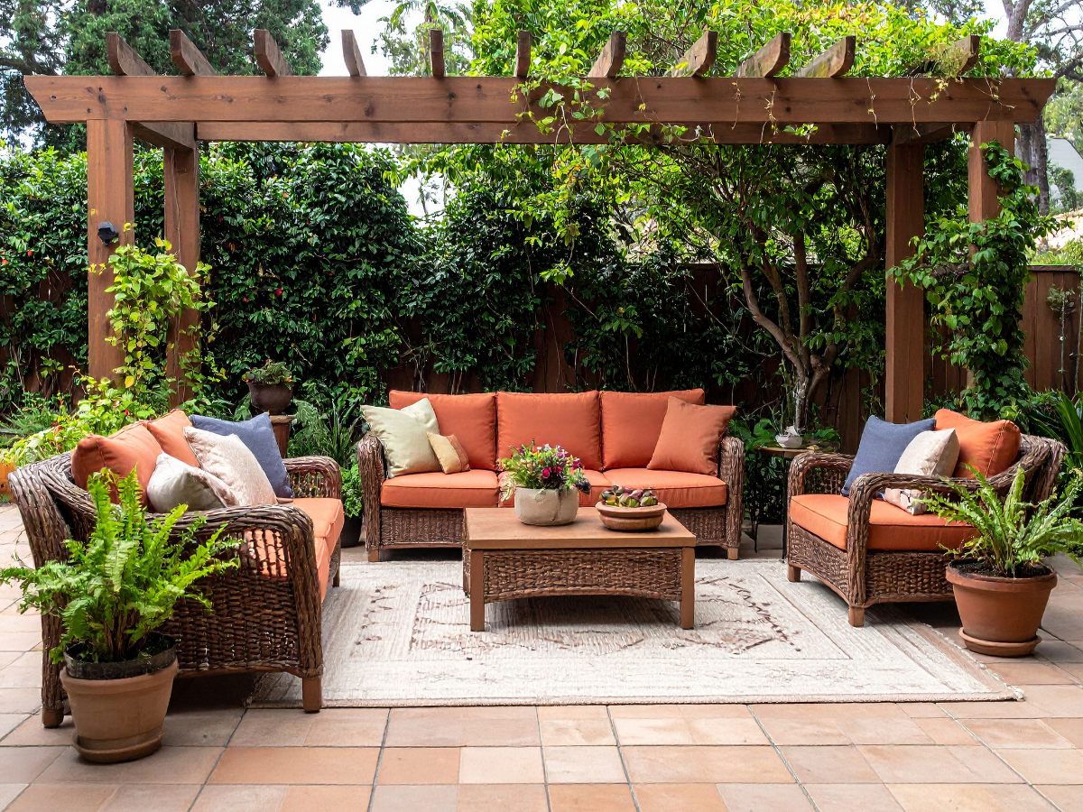 Outdoor garden  rattan  furniture with orange cushions, a garden table and outdoor rug on patio
