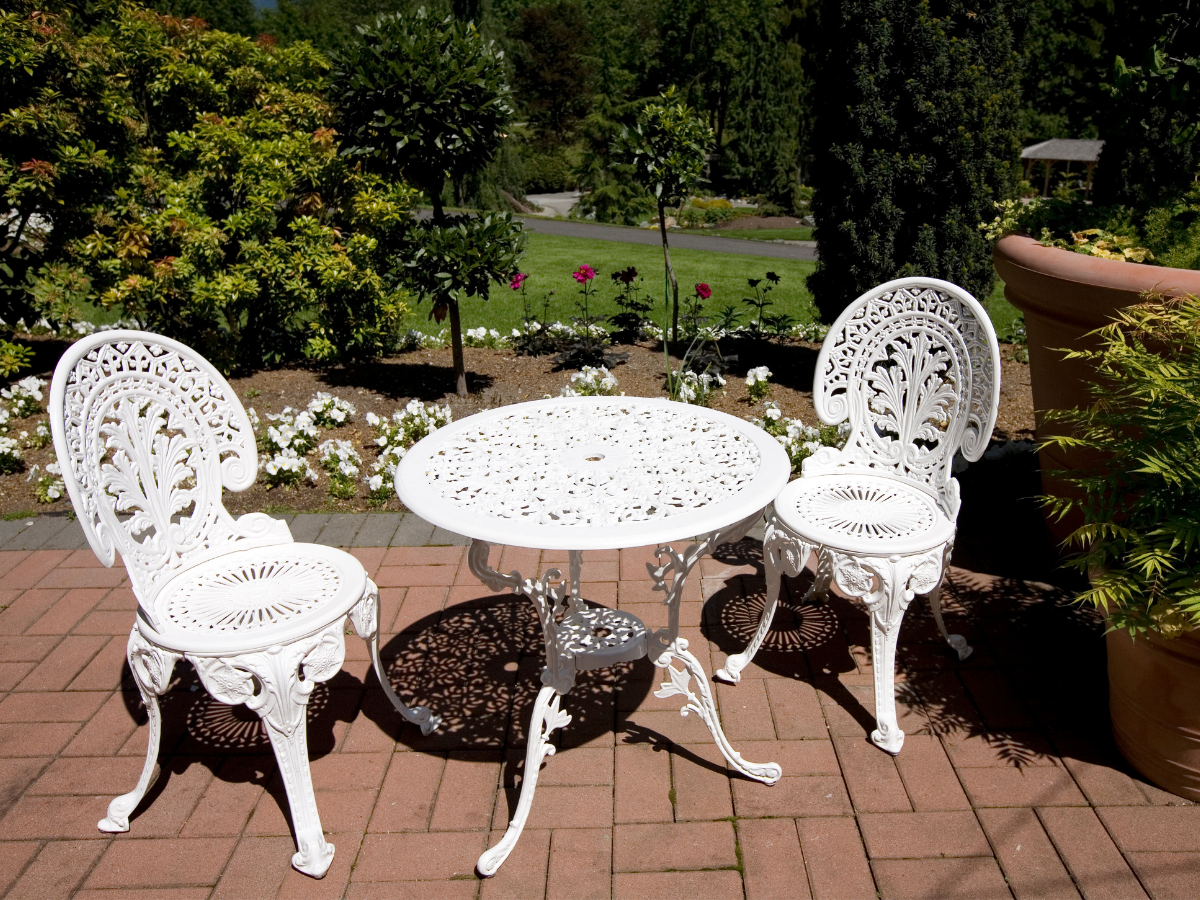 two-seater white metal bistro table and chairs on small patio 
