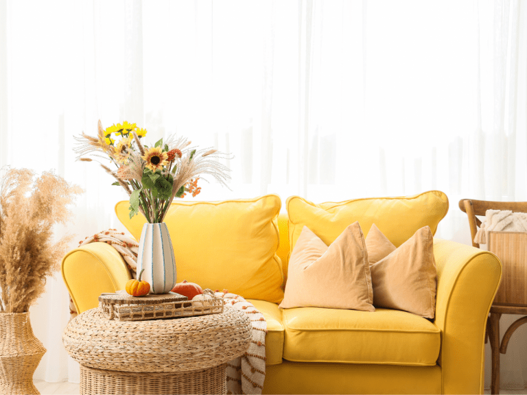 A styled corner of a living room — a light yellow sofa fresh flowers in a simple vase, Feels like a boutique B&B rather than someone's front room.