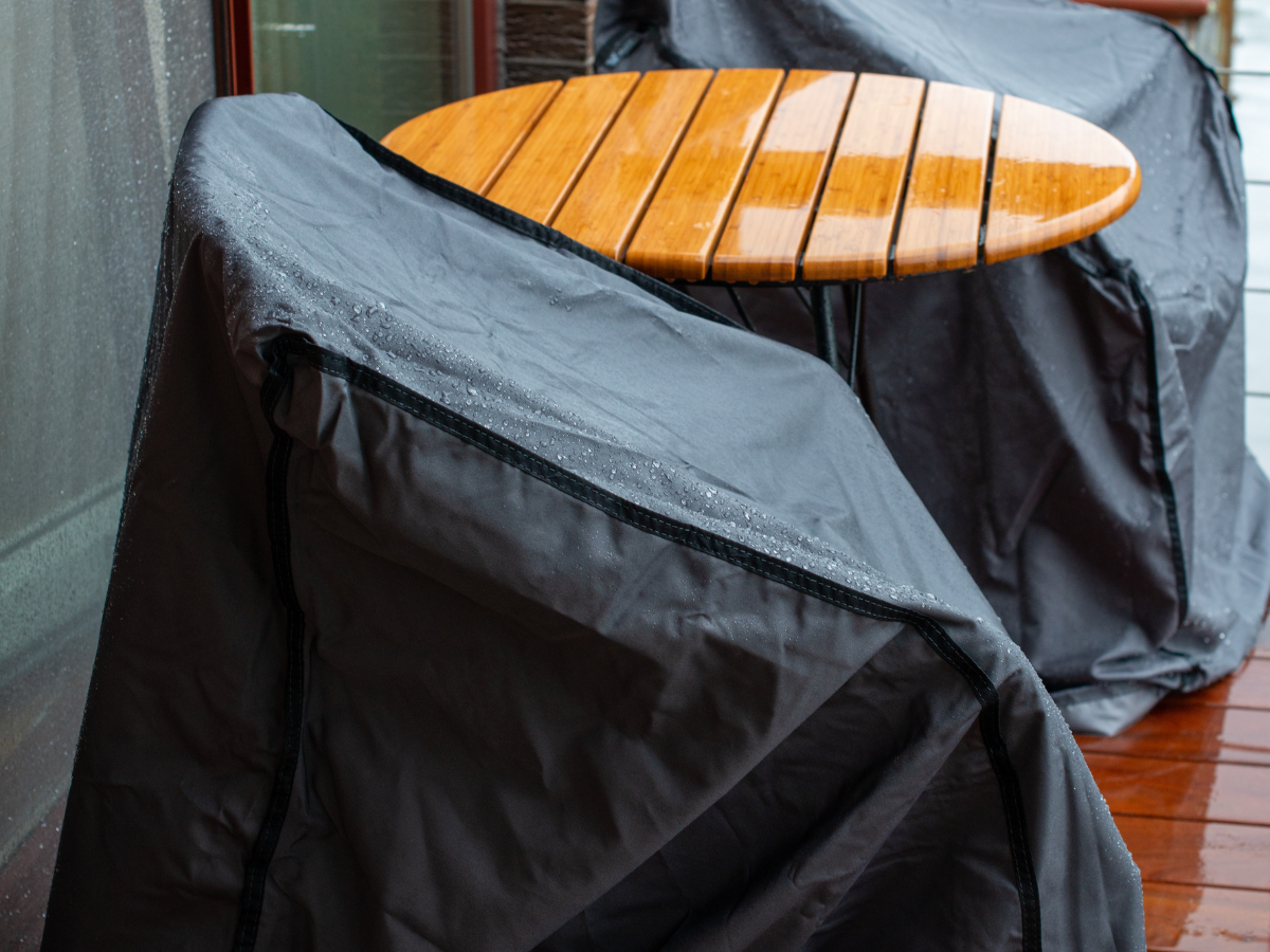 garden furniture care and maintenance UK — rattan garden sofa with cushions being covered with protective furniture cover]