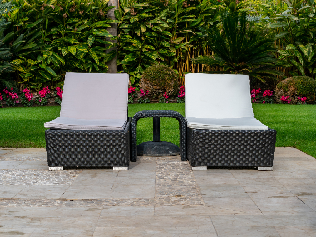 outdoor sun lounger garden holiday feel UK rattan reclining lounger with cushions on sunny patio