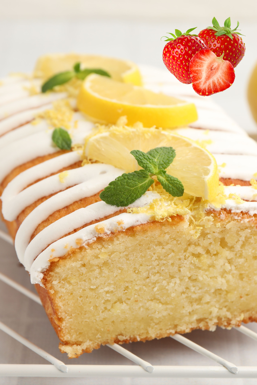 Fresh summer lemon drizzle cake cooling on rack with strawberries and cream
