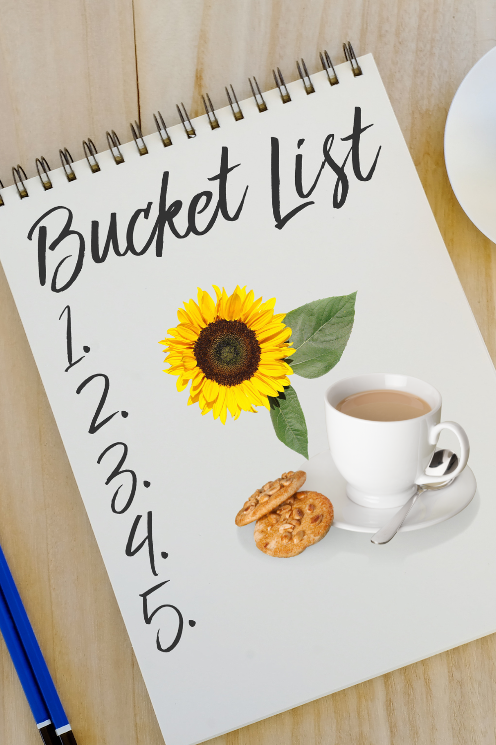 Printed summer bucket list checklist on a clipboard next to a cup of tea and sunflower