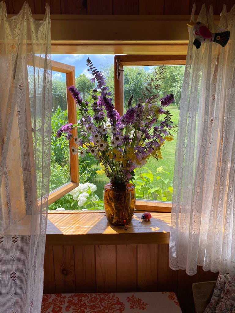 Colorful wildflowers in a vase by an open window, inviting warmth and summer vibes into the room.
