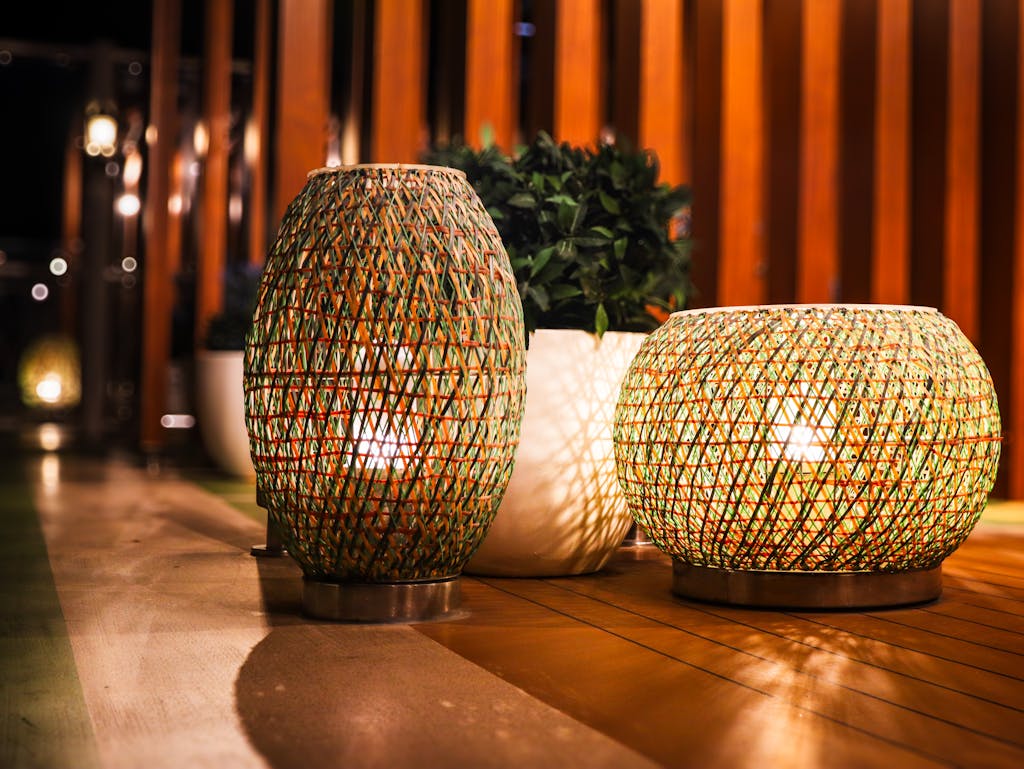 Elegant outdoor lighting setup with woven lanterns casting warm glows on a wooden patio.