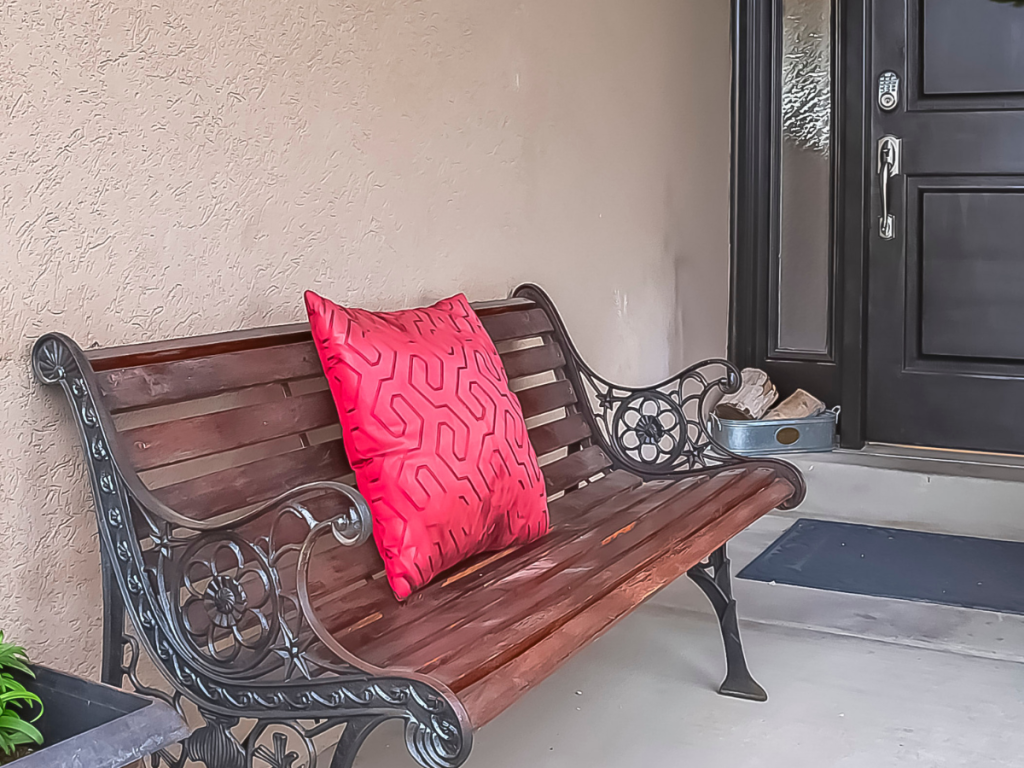 A quaint outdoor patio featuring a Wooden bench seating and cushion