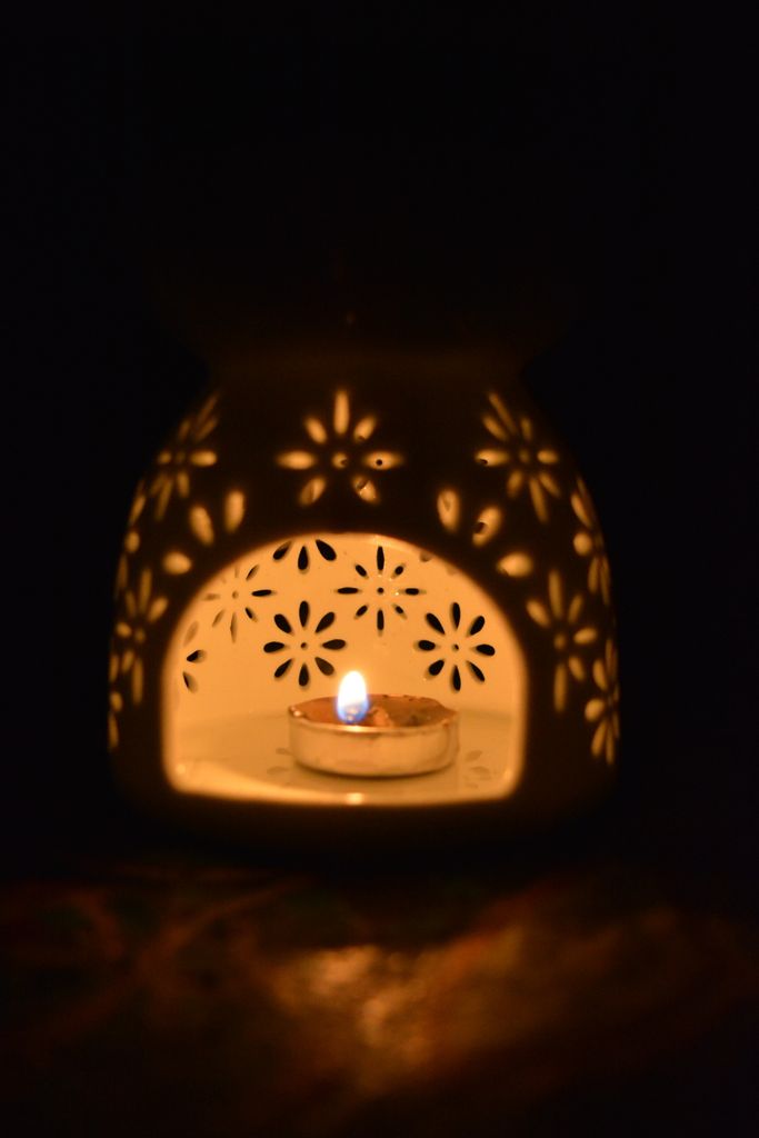 A glowing candle inside an artistic floral ceramic oil burner creates a meditative summer night ambiance feel