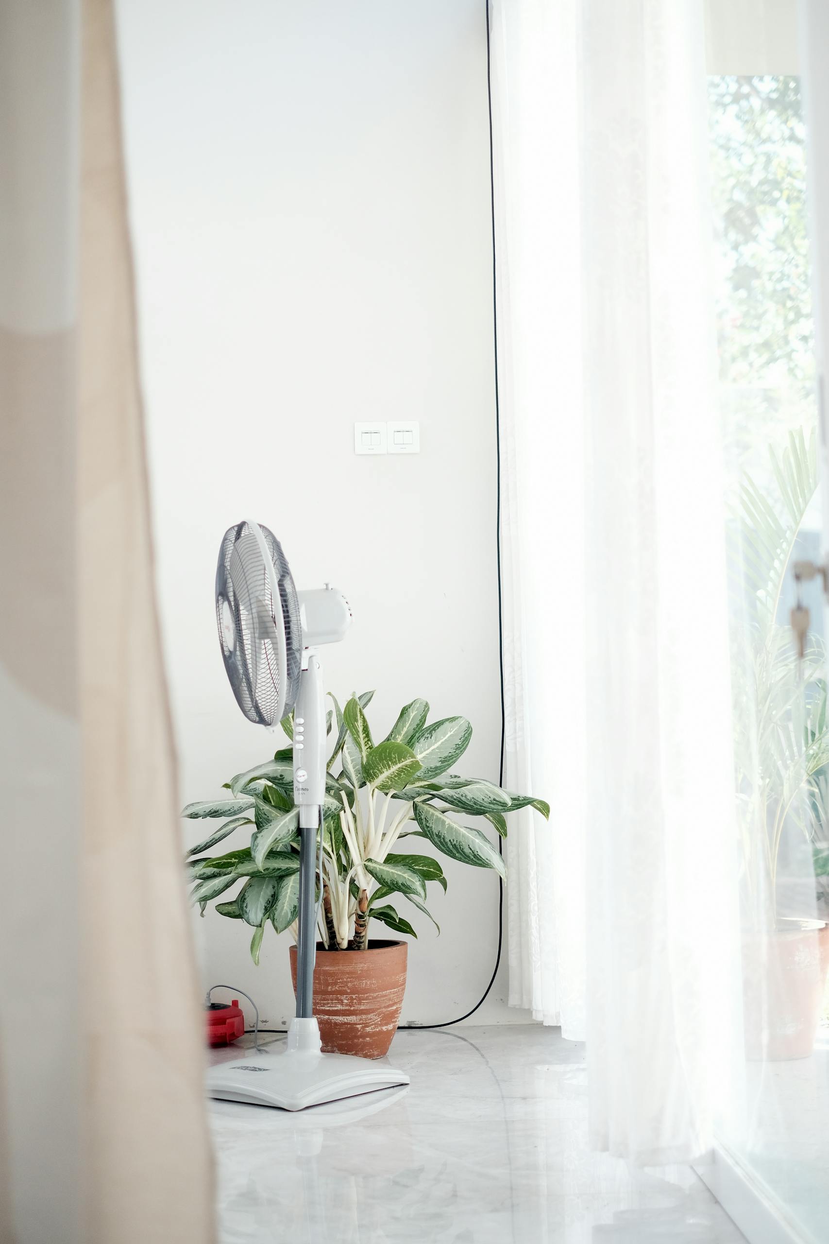 Quite basic pedestal fan in cool calm budget bedroom UK heatwave staycation feel