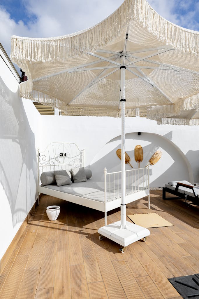Chic outdoor balcony relaxation area with white parasol and sunbed.