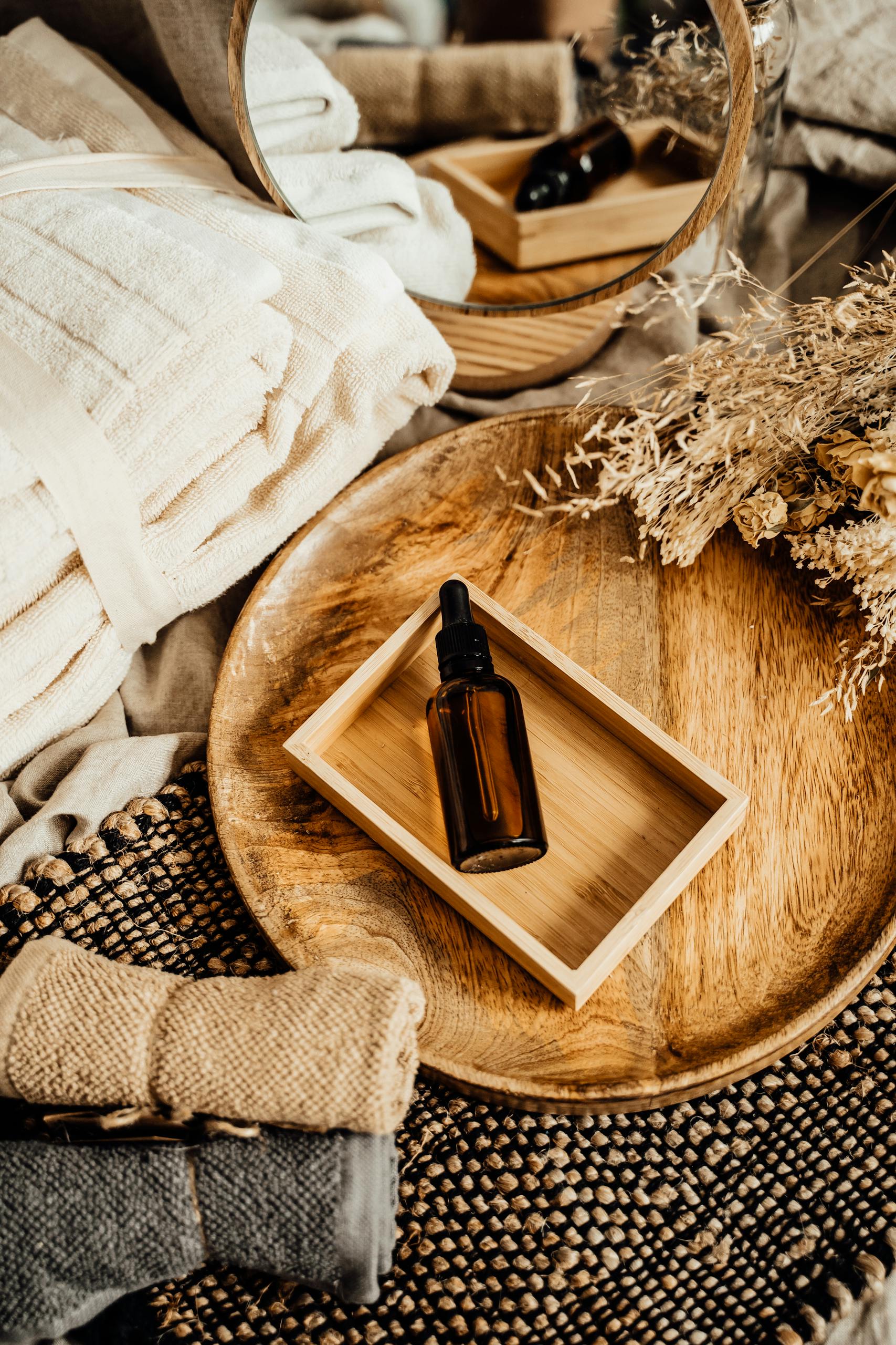 Styled bedside table with tray, essential oil sent and dried flowers in an organised bedroom retreat Elegant spa composition featuring glass bottle dropper