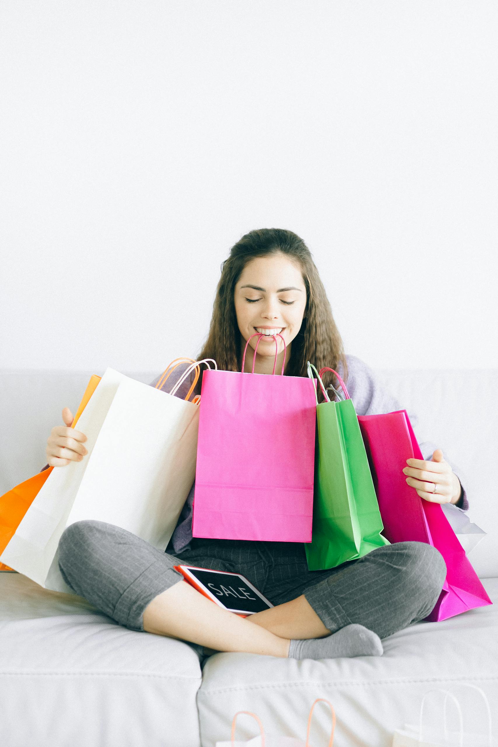 Happy woman sitting with colorful shopping bags after successful shopping spree for holiday at home/staycation 