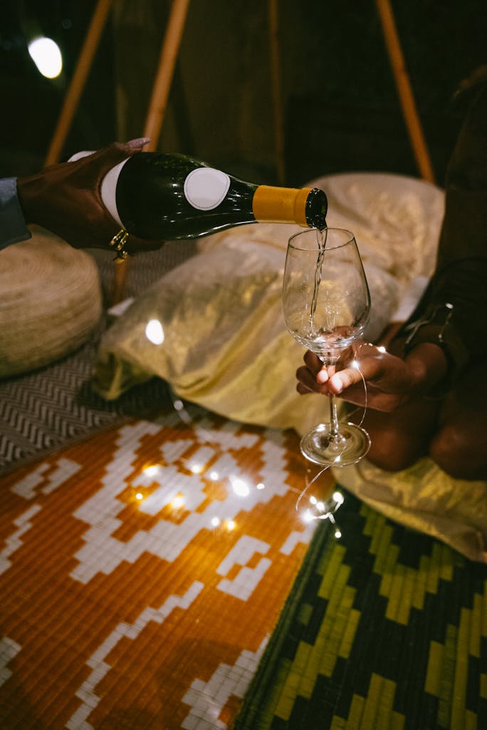 Intimate scene of wine being poured into a glass amidst a cozy outdoor setting, perfect for social gatherings. summer night in ideas at home garden fairy lights for a staycation evening