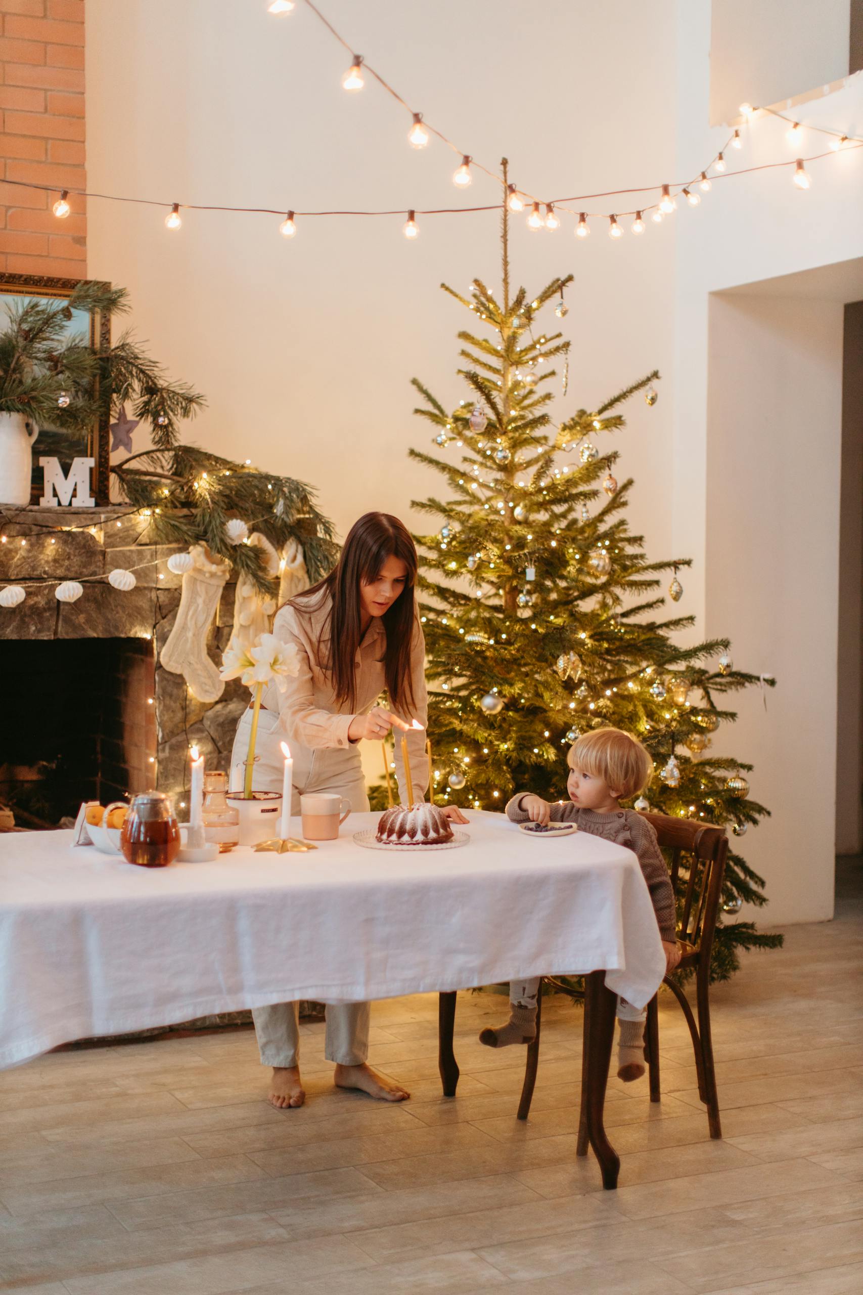 Mother and child celebrating with cake by Christmas tree, festive decor.