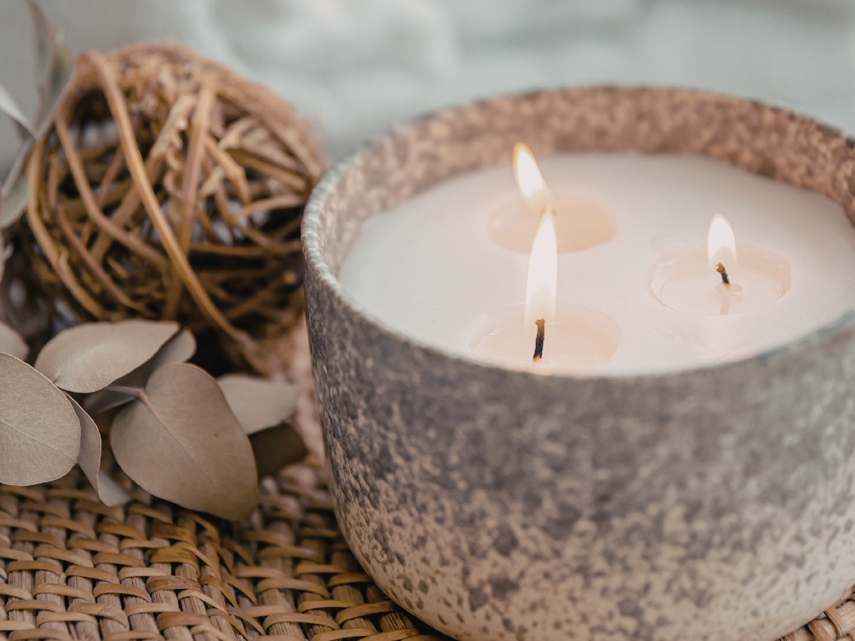 hree wick soy wax candle burning on coffee table in cosy living room — home candle ideas that make your home feel like a permanent escape