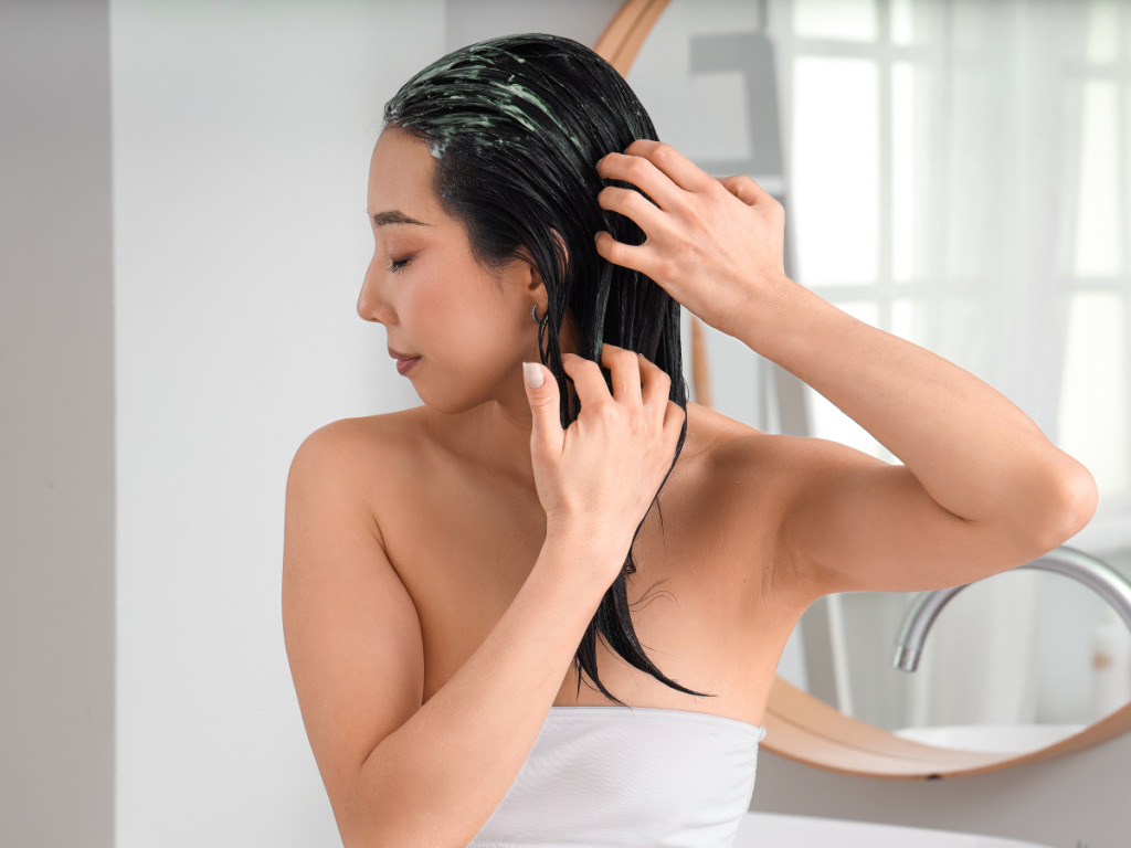Woman applying a natural hair mask treatment in a summer bathroom